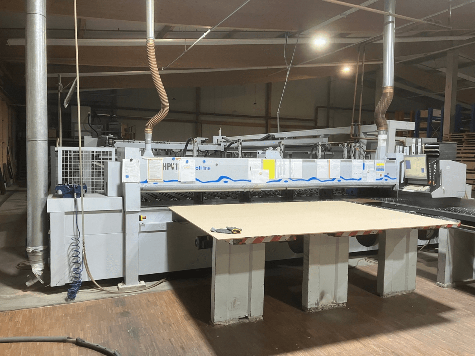 Sega a pannelli HOLZMA HPV11 in un'officina, vista frontale con ampia superficie di lavoro piana e pannello di controllo visibile.