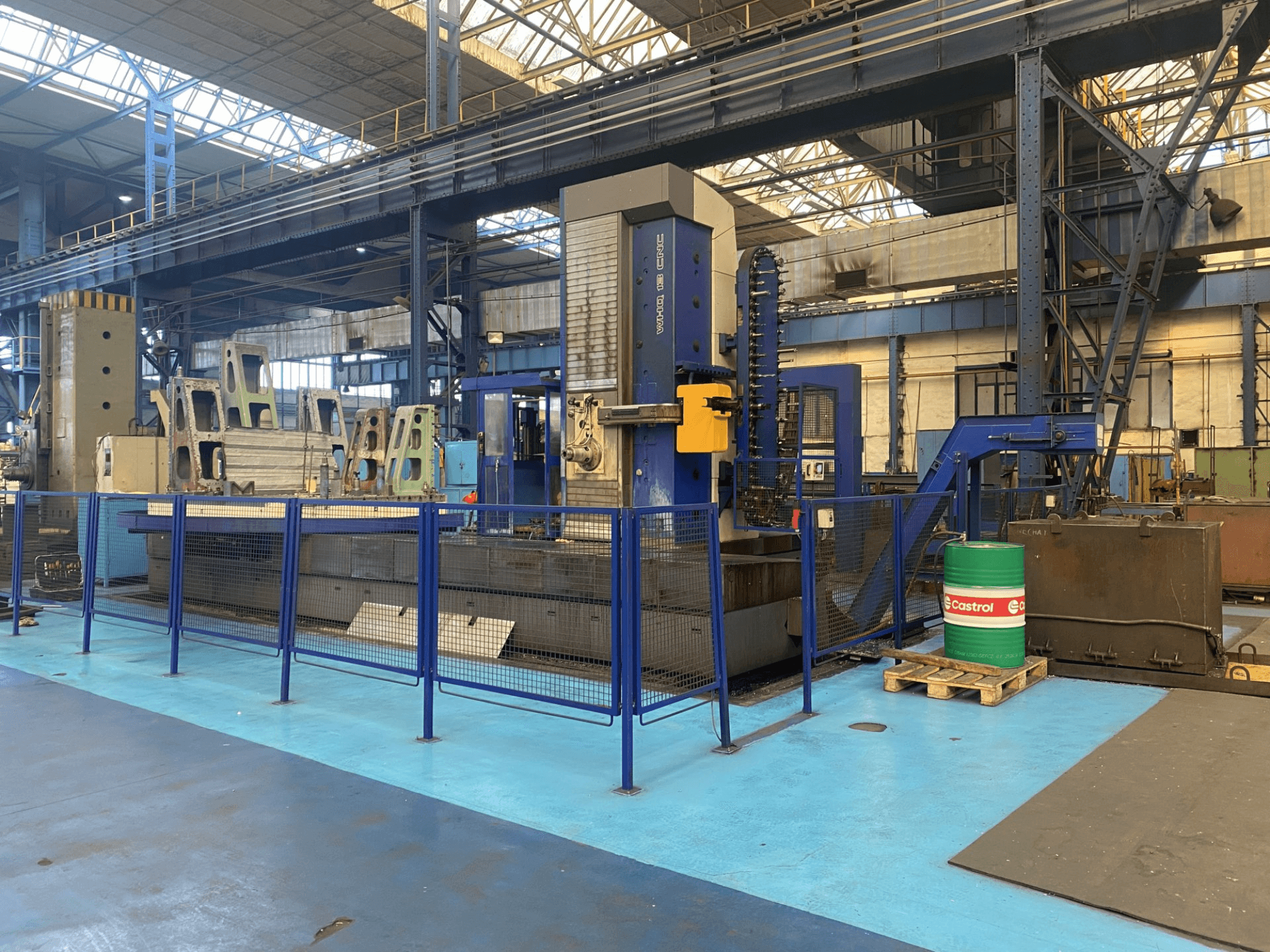 Alesatrice a controllo numerico TOS WHQ 13 in un'officina, vista frontale, con telaio blu e recinzione di sicurezza circostante.