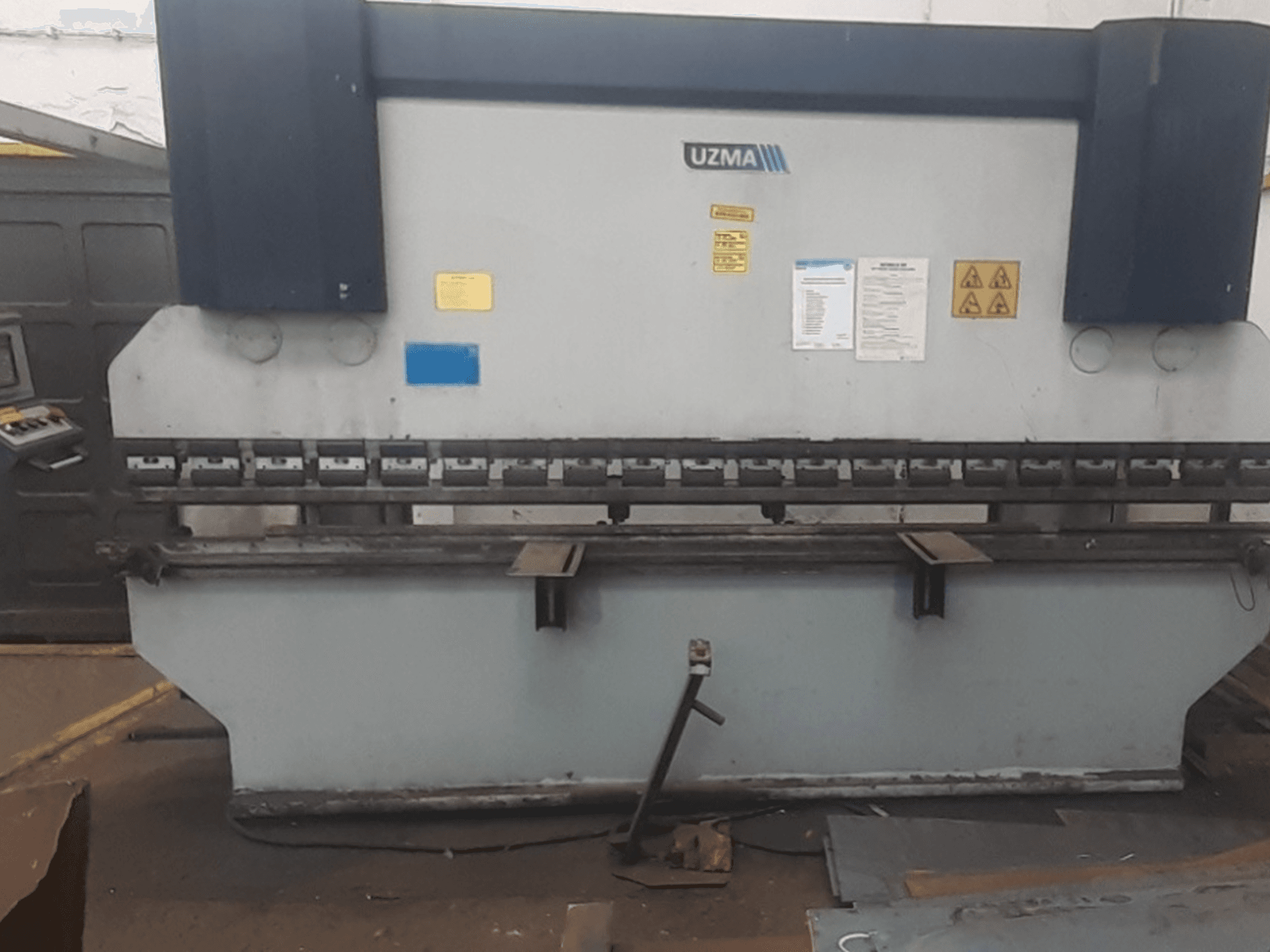 Pressa piegatrice UZMA HAP 40160 in vista frontale, con comandi, avvisi di sicurezza e utensili per la piegatura dei metalli.