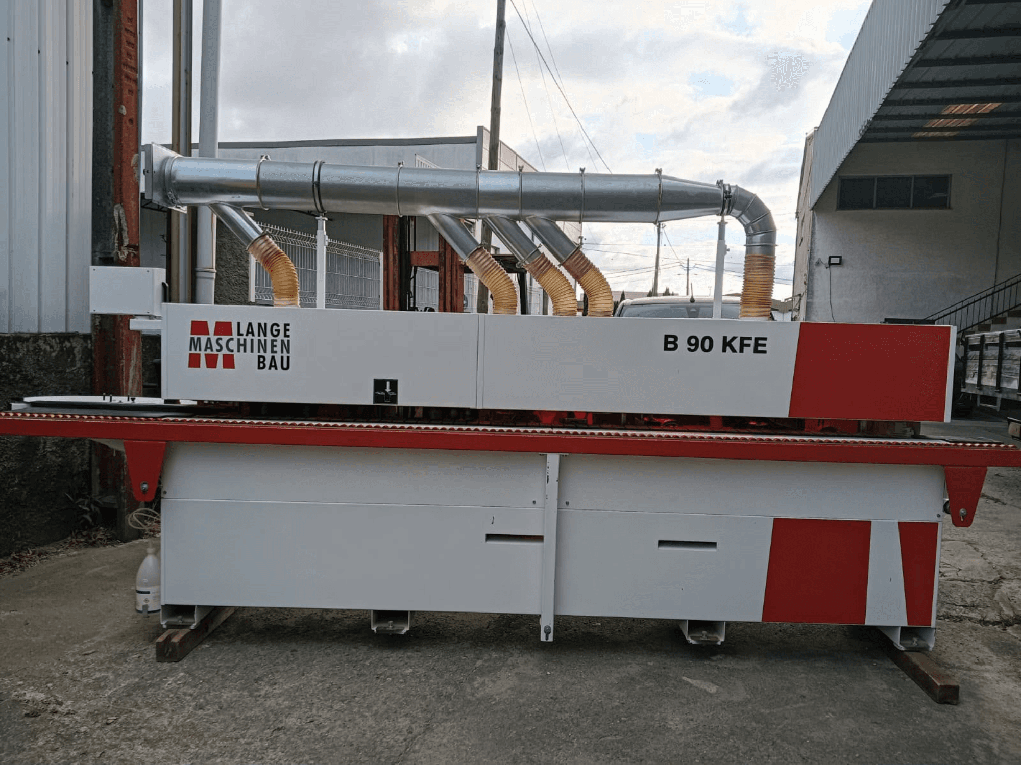 Bordatrice LANGE Maschinenbau B 90 KFE vista di profilo con doppio tubo di scarico e dettagli rossi, collocata in un ambiente di lavoro industriale.