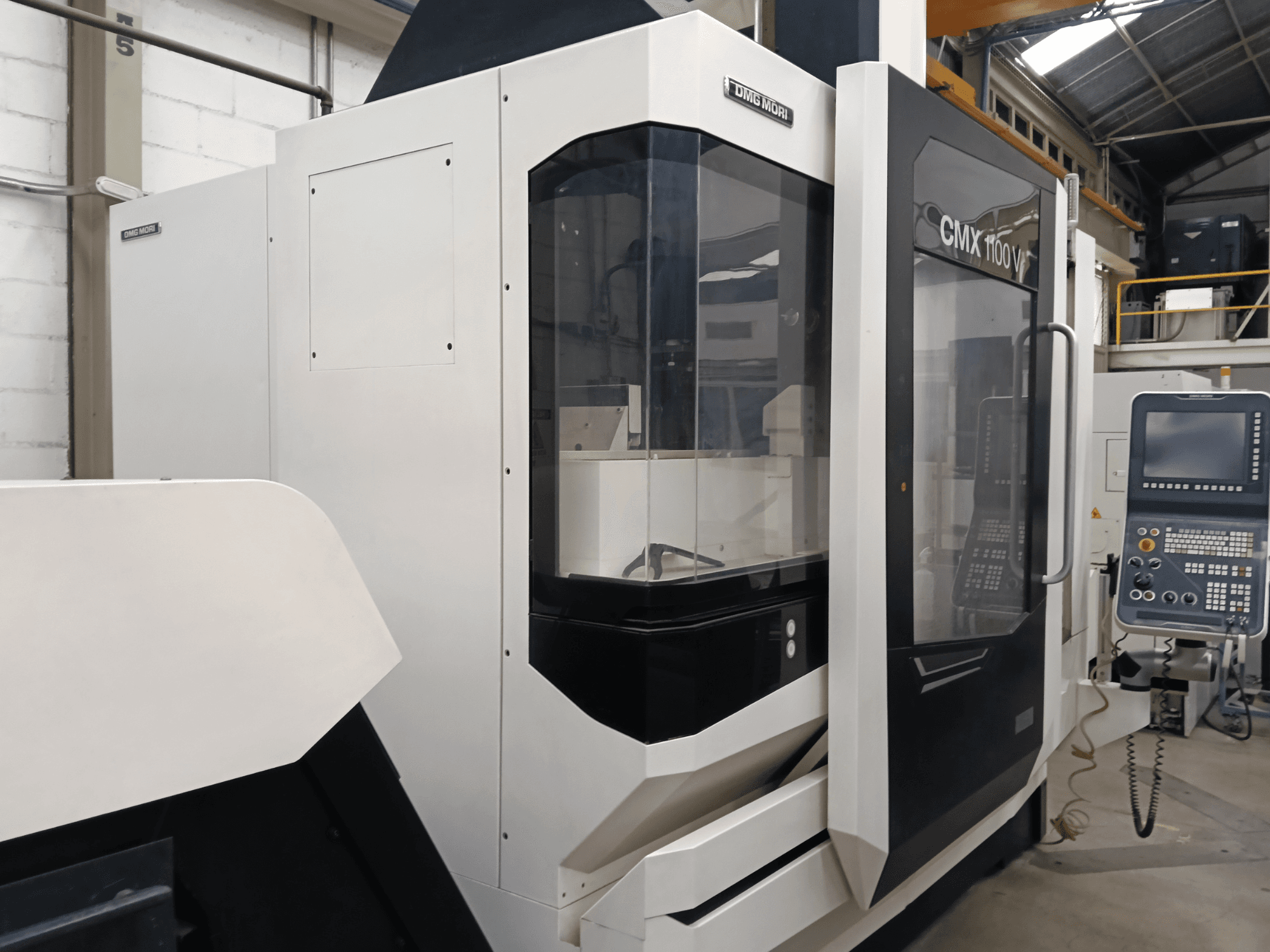 Centro di lavorazione verticale DMG MORI CMX 1100 V, vista frontale, con pannello di controllo e copertura in vetro.