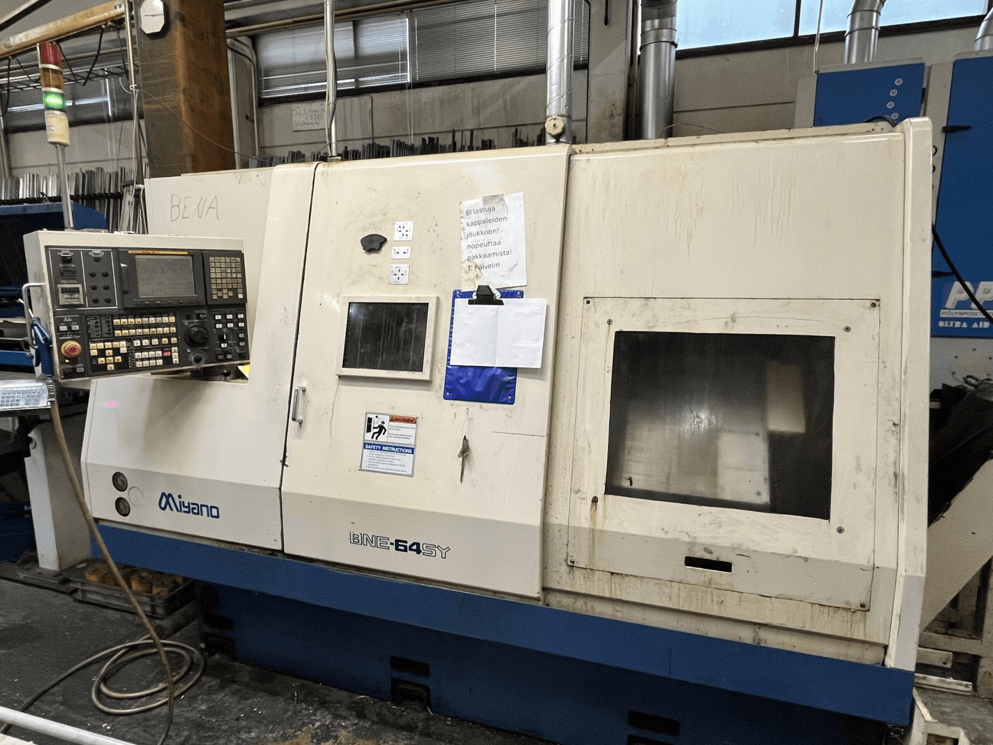 Tornio CNC Miyano BNE-64SY, vista frontale, pannello di controllo con pulsanti, LCD e adesivi di manutenzione sul mobile.