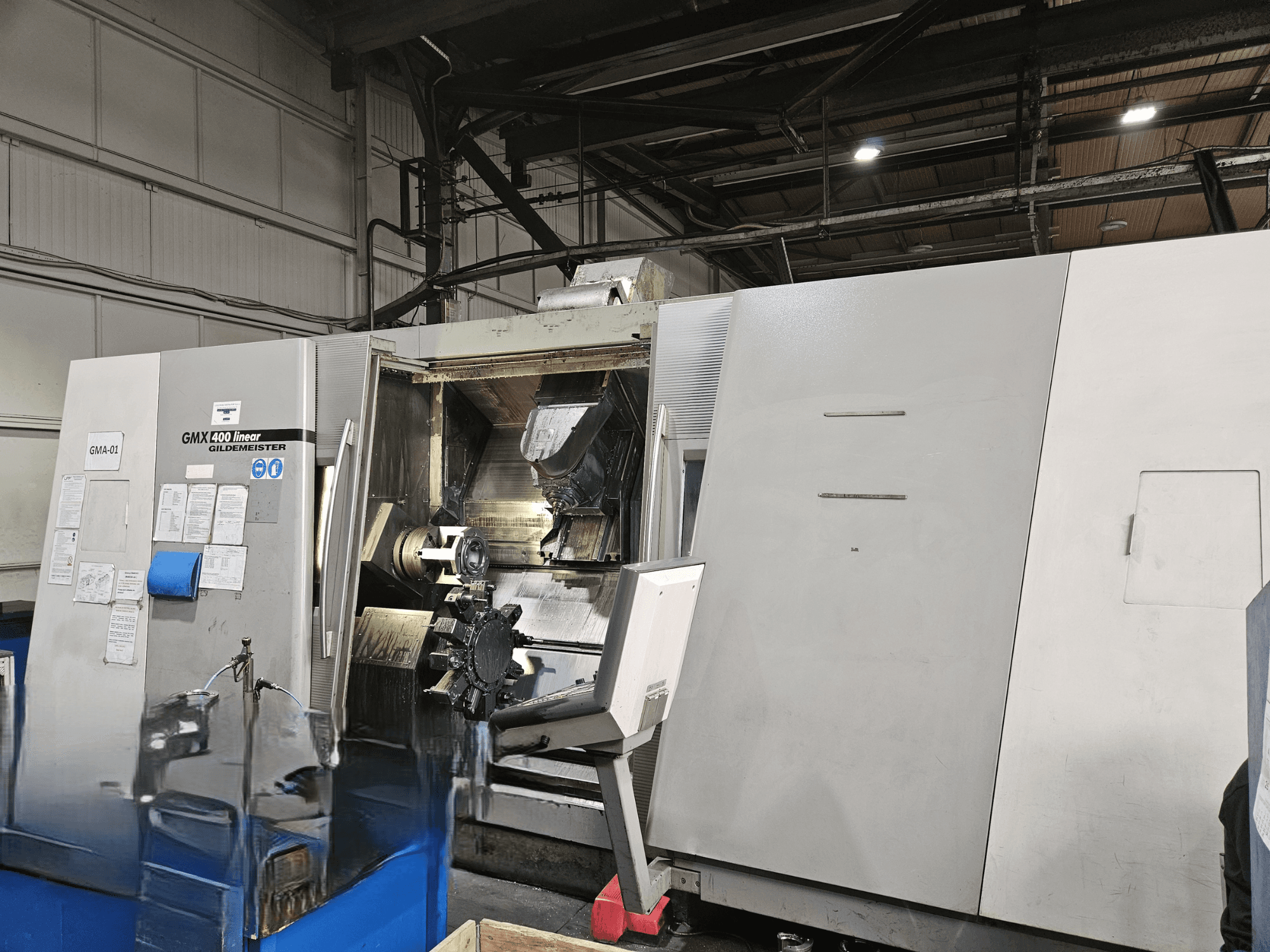 Centro di tornitura Gildemeister GMX 400 Linear in vista frontale, che mostra l'accesso aperto all'area di lavorazione e agli utensili all'interno.