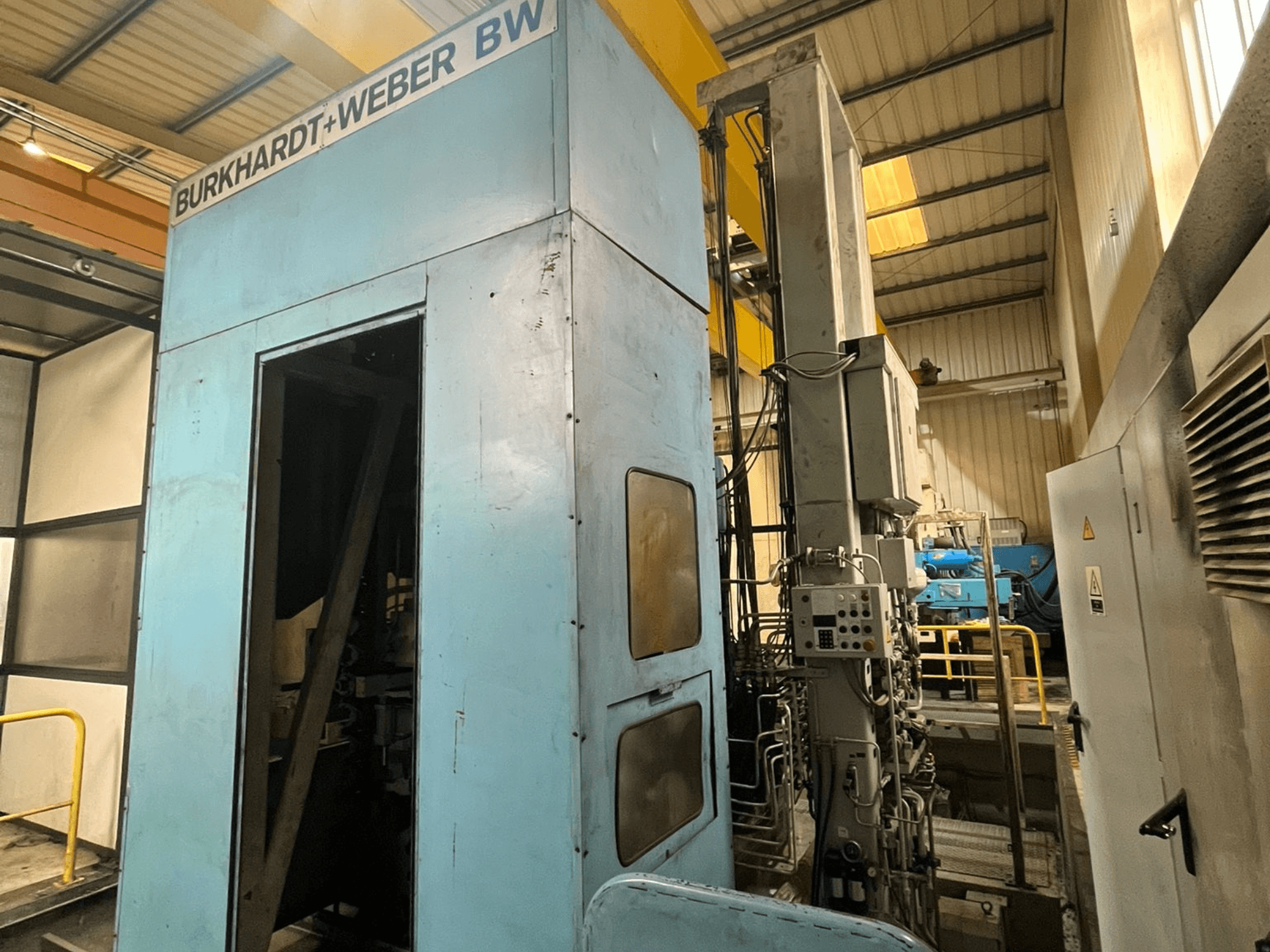 Centro di lavorazione orizzontale Burkhardt-Weber MC100, vista laterale che mostra l'esterno blu e il pannello di controllo con i tubi a vista.