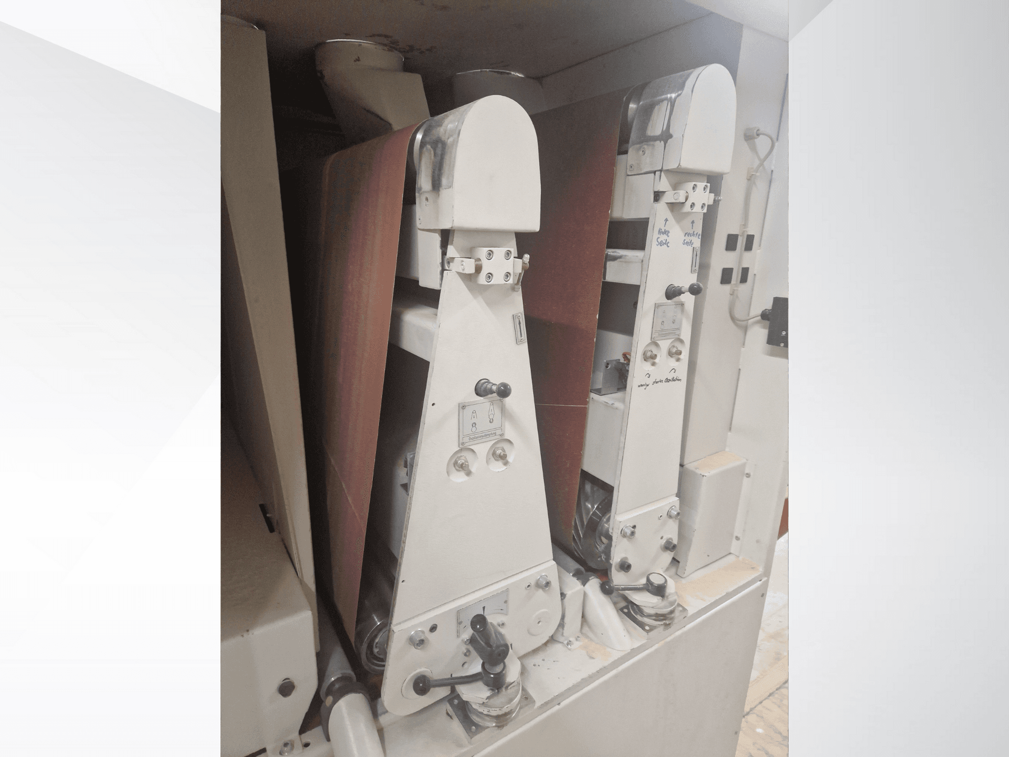 Due levigatrici industriali con nastri abrasivi rossi, vista frontale, con comandi e componenti metallici.