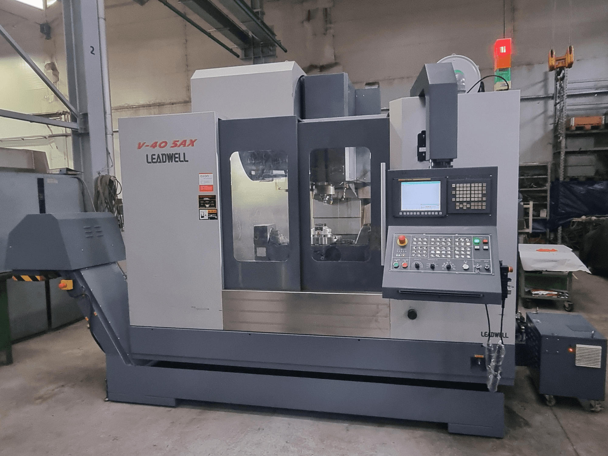 Centro di lavorazione verticale Leadwell V40 5AX, vista frontale, con pannello di controllo e area di lavorazione dotati di luci di sicurezza.