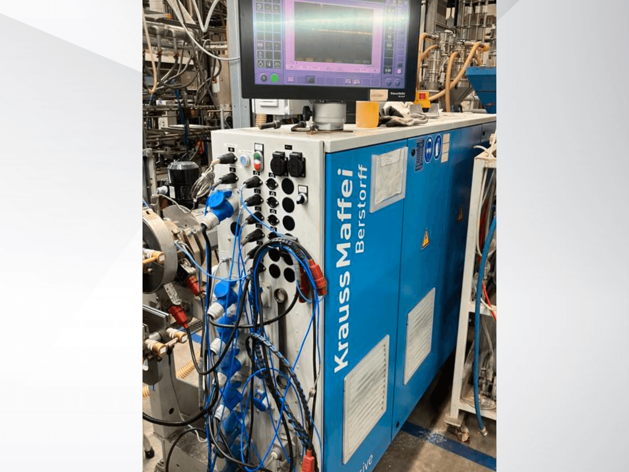 Macchina industriale Krauss Maffei Berstorff con pannello di controllo e monitor, con vari pulsanti e tubi collegati, vista laterale.