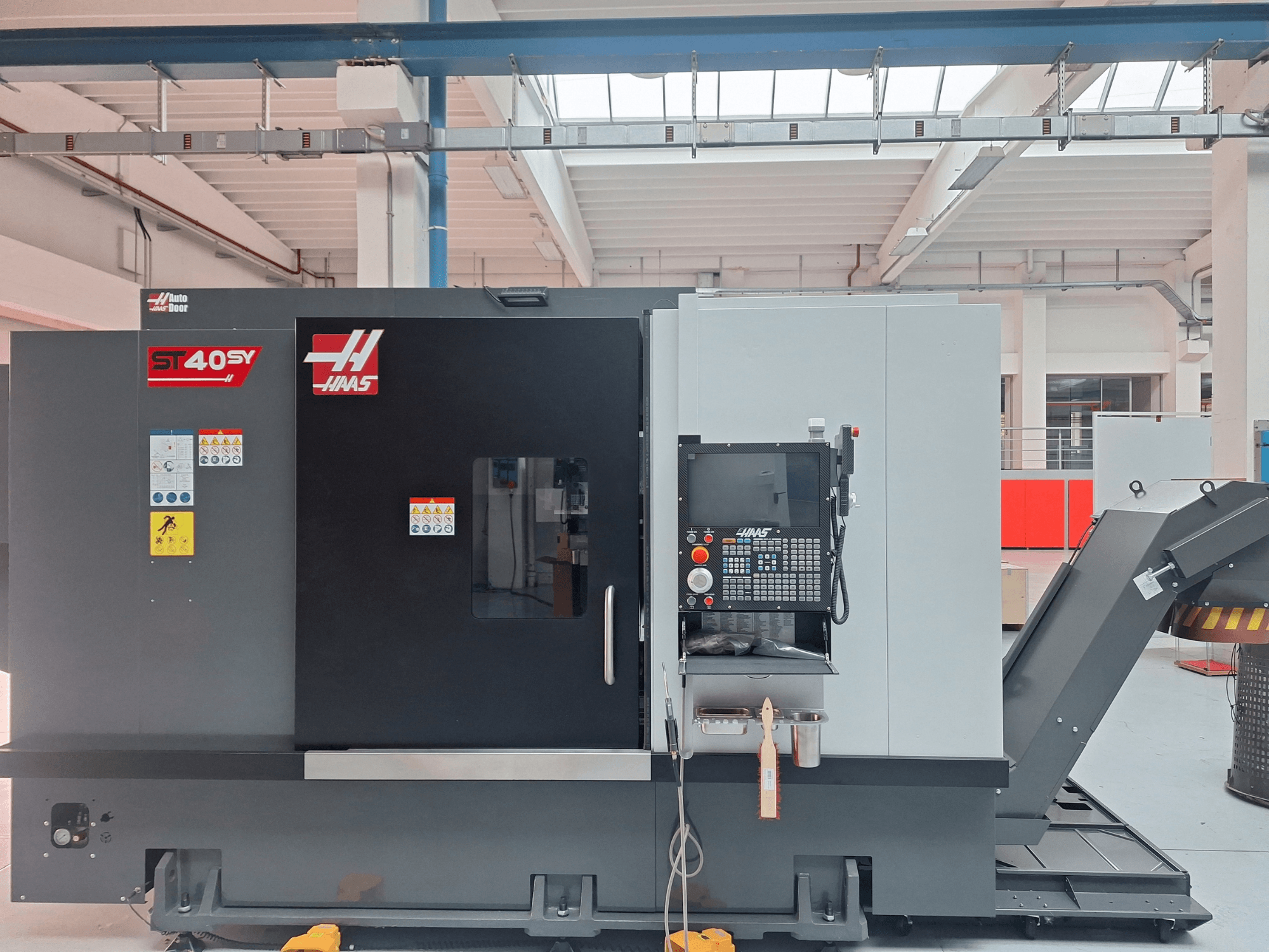 Tornio orizzontale Haas ST-40SY visto di lato, con pannello di controllo ed etichette di sicurezza.