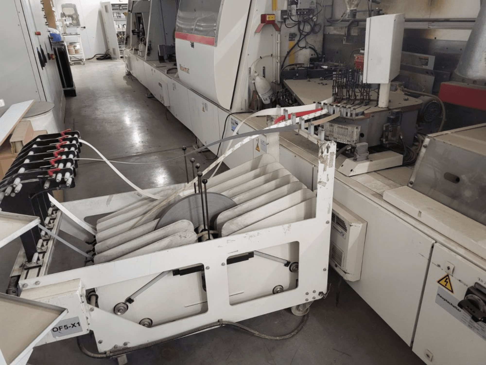 Bordatrice IMA Novimat/I/680/650/R3, vista laterale che mostra i rulli di alimentazione e il pannello di controllo in un ambiente di officina.