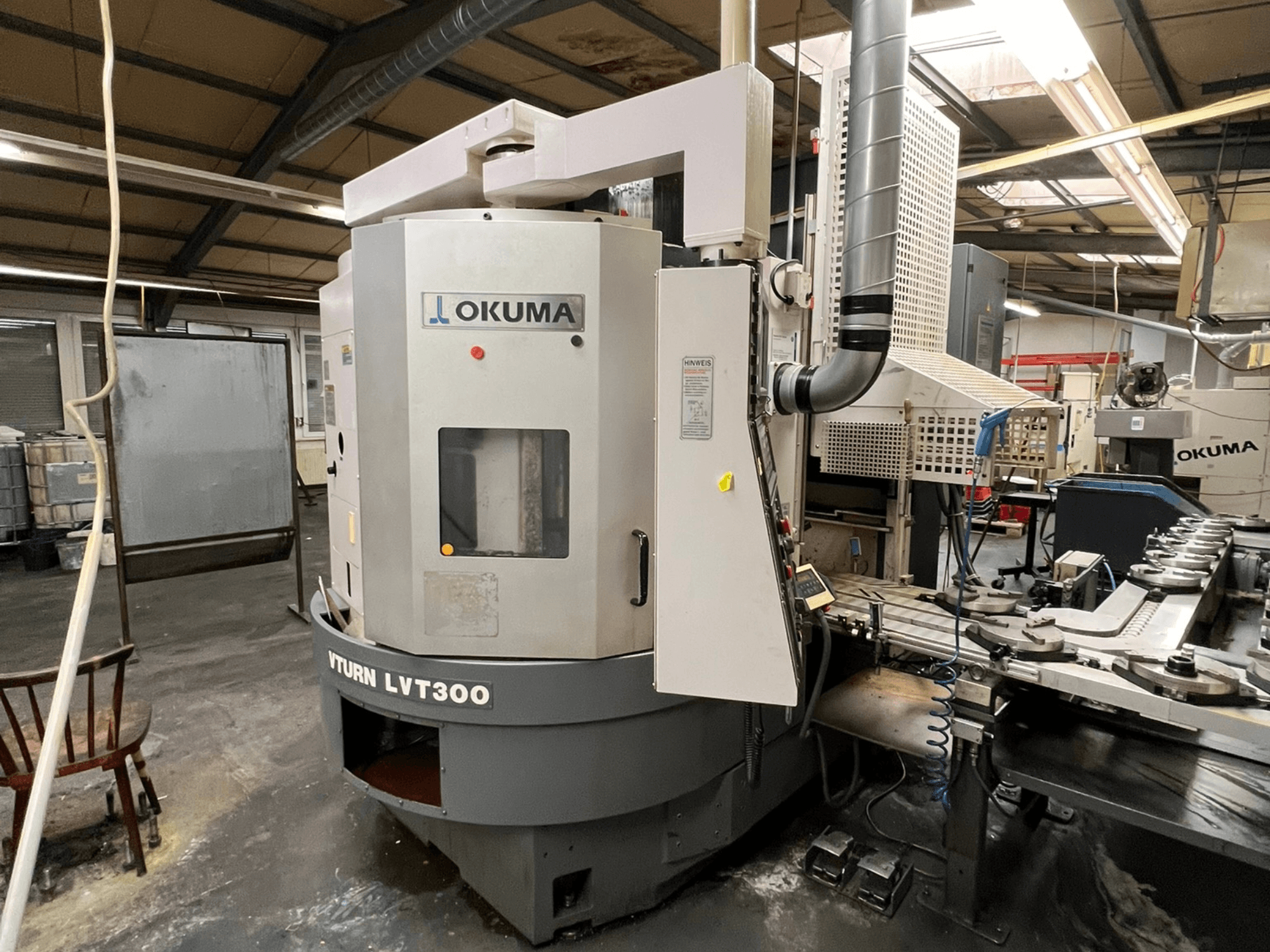 Tornio CNC Okuma Vturn LVT300, vista laterale in ambiente industriale, con pannello di controllo e sistema di raffreddamento.