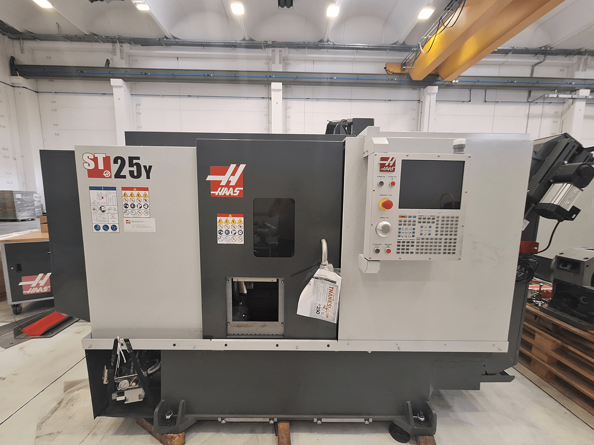 Tornio orizzontale Haas ST-25Y, vista frontale, con pannello di controllo ed etichette di sicurezza. Ideale per la lavorazione di precisione.