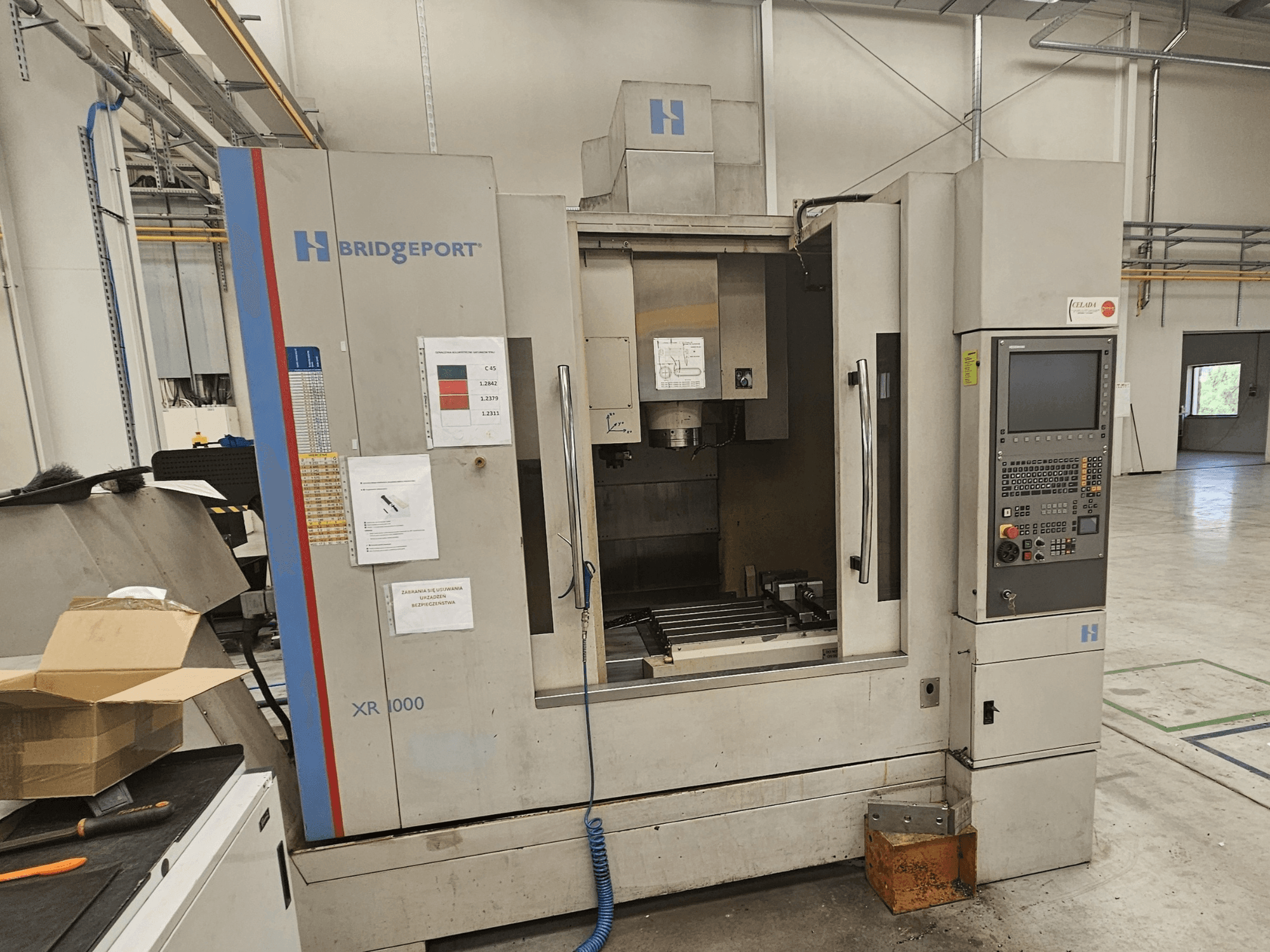 Centro di lavoro verticale Bridgeport XR 1000, vista frontale, con pannello di controllo e area di lavoro visibile con tavolo da taglio.