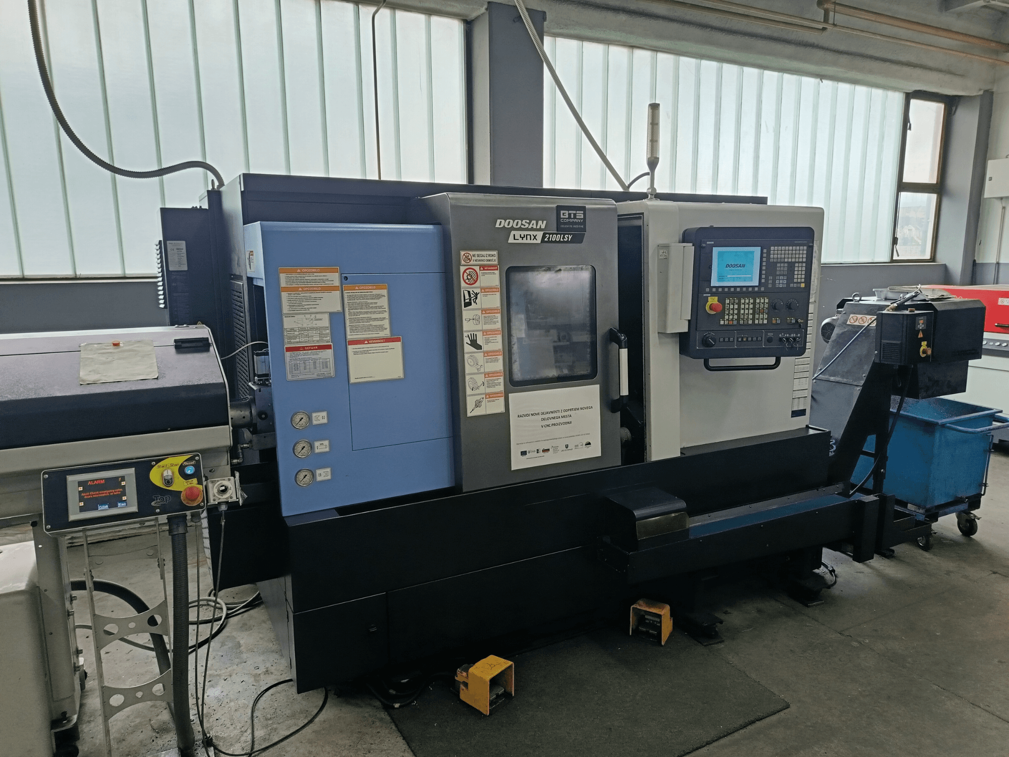 Centro di fresatura DOOSAN LYNX 2100 LSY, vista laterale che mostra il pannello di controllo e i pulsanti operativi, con etichette informative visibili.