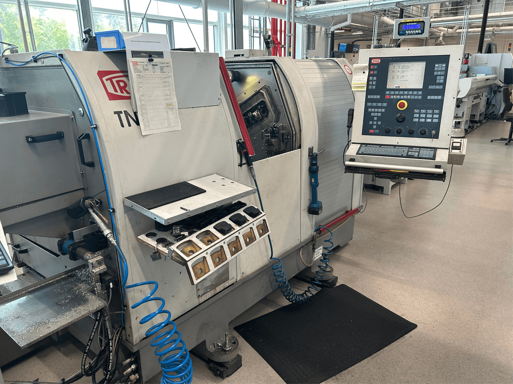 Tornio orizzontale TRAUB TNK 36, vista frontale, con pannello di controllo, portautensili e area di lavoro con trucioli metallici.
