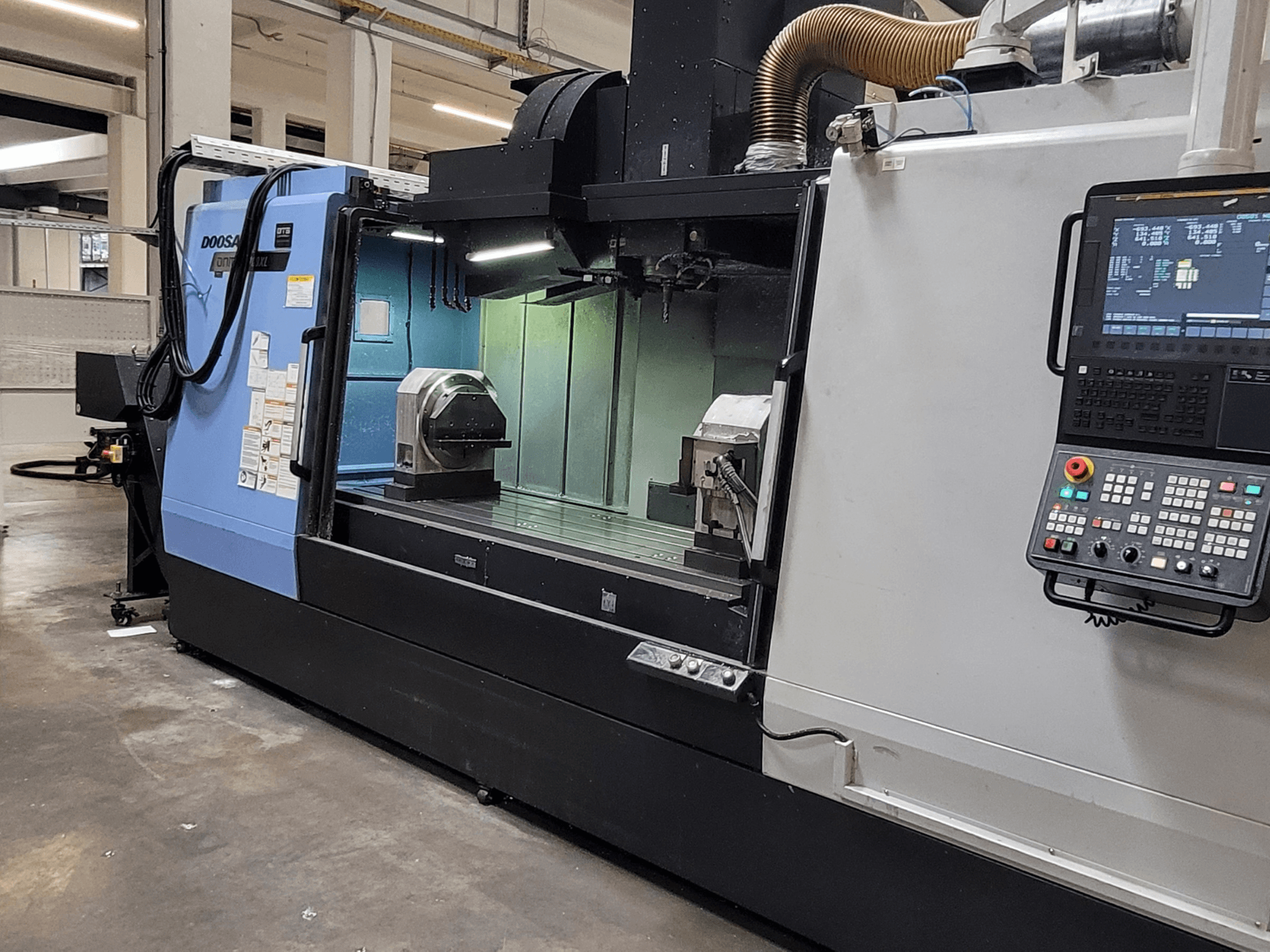 Centro di lavorazione verticale DOOSAN DNM 6700 XL, vista frontale che mostra il pannello di controllo, il piano di lavoro e l'area di lavorazione.