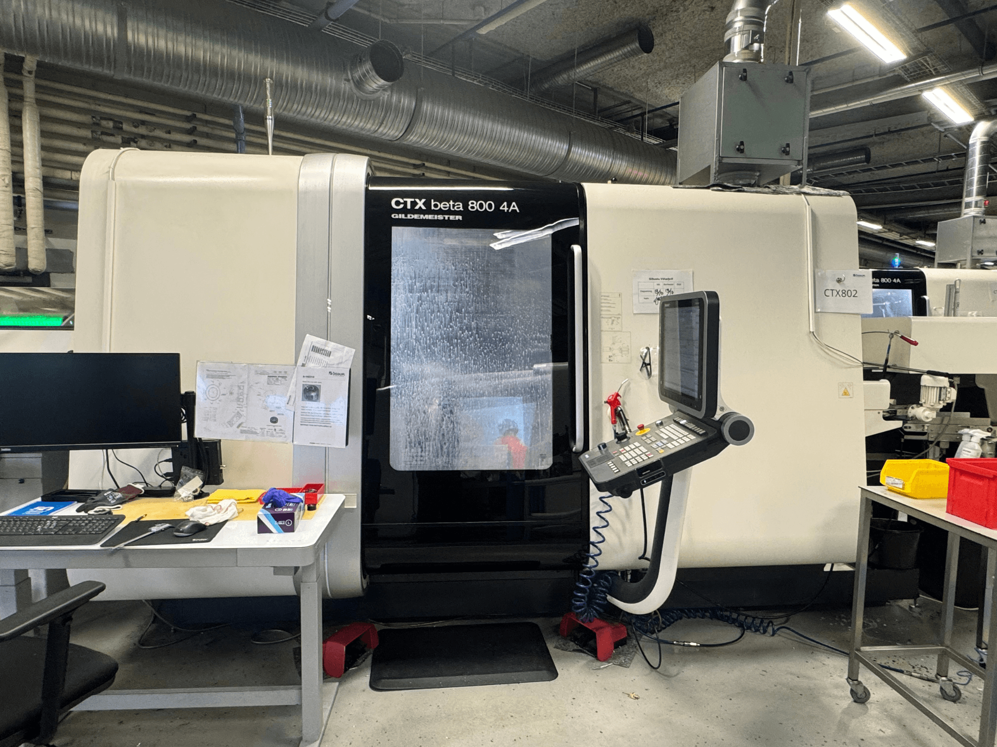 Macchina CNC CTX beta 800 4A in un'officina, vista laterale che mostra il pannello di controllo e lo spazio di lavoro ingombro di utensili e documenti.