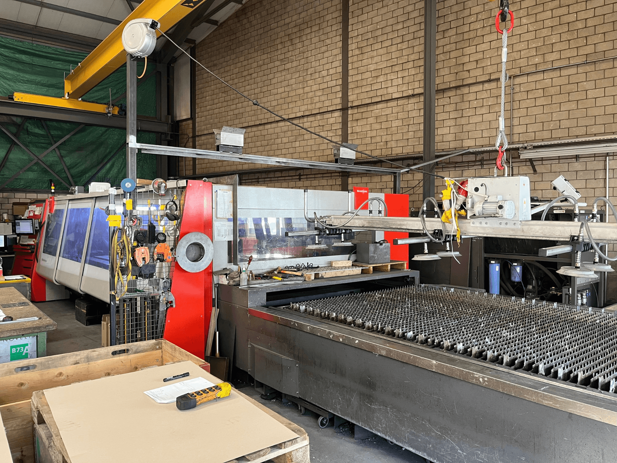 Macchina per il taglio laser a CO₂ Bystronic ByAutonom 4020, vista laterale con piano di lavoro, pannello di controllo e gru a ponte sullo sfondo.
