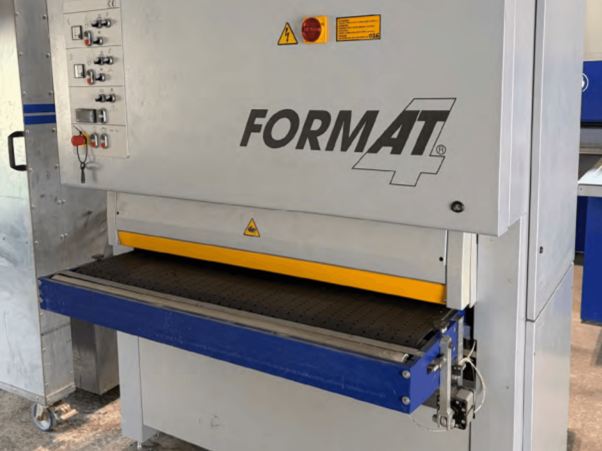 Levigatrice a nastro FORMAT4 Finish 1302 vista frontale, con pannello di controllo, nastro abrasivo giallo e tavolo trasportatore blu.