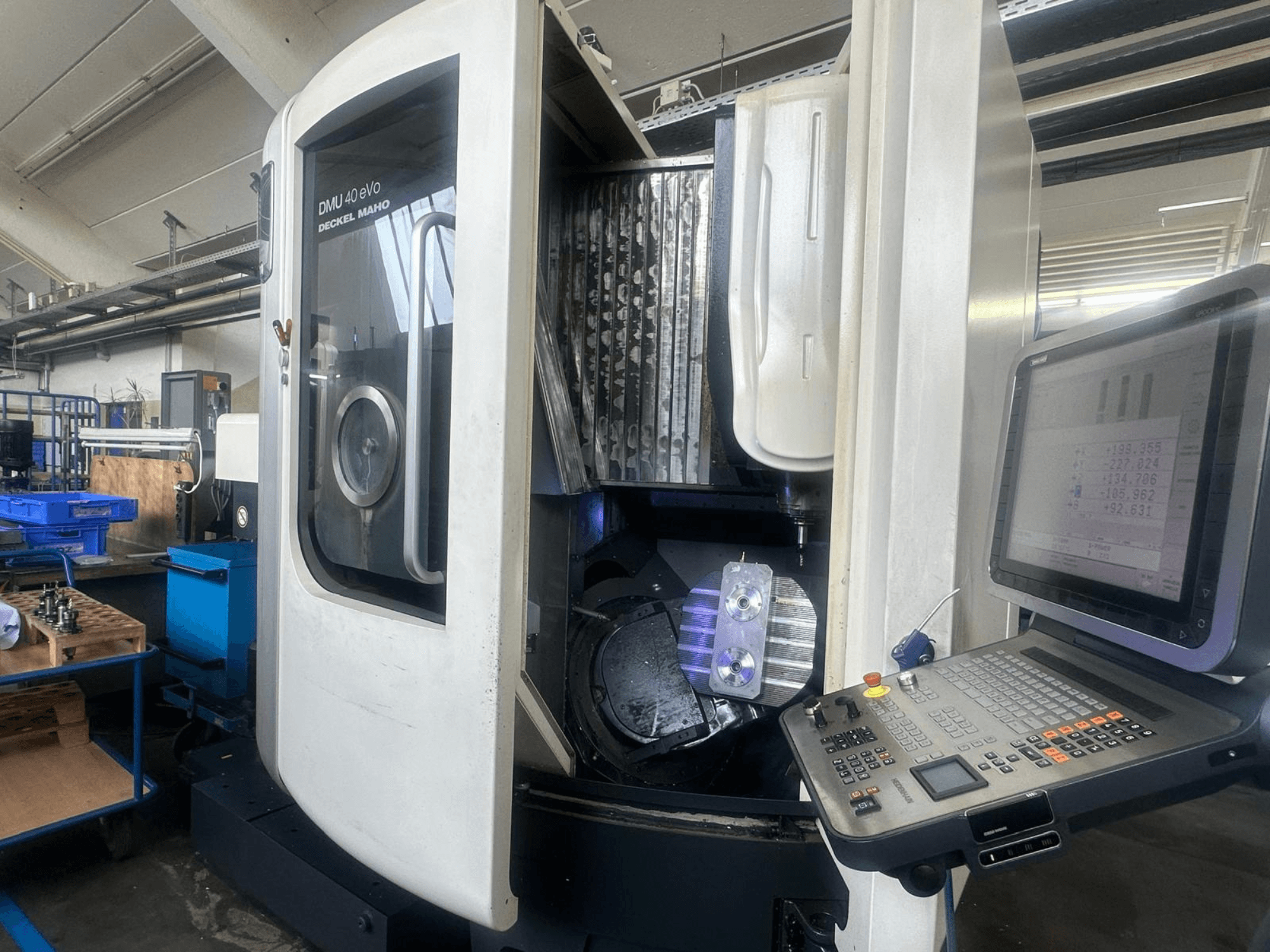 Fresatrice DMU 40 eVo di Deckel Maho in un'officina, vista frontale, con pannello di controllo e pezzo di metallo nel mandrino.