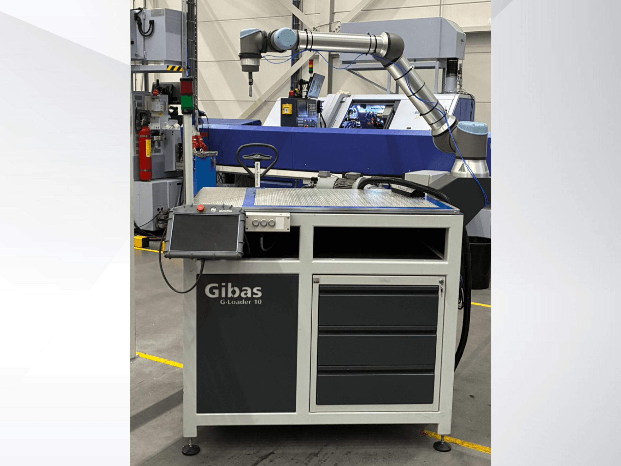 Gibas G-Loader 10 con braccio robotico, vista frontale; dispone di controllo touchscreen e cassetto di stoccaggio in ambiente industriale.