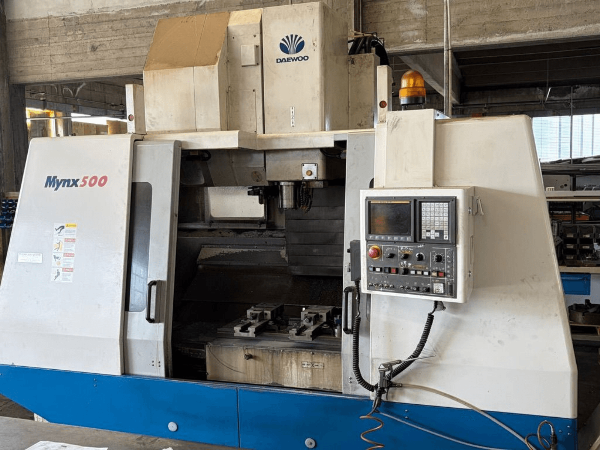 Centro di lavorazione verticale DAEWOO Mynx 500 visto frontalmente, con pannello di controllo e portautensili all'interno.