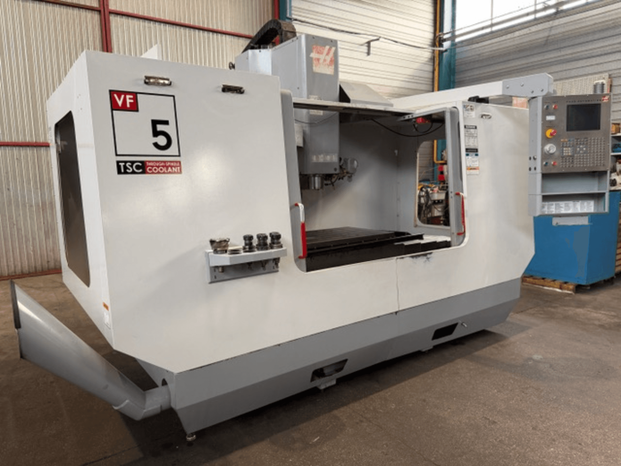 Centro di lavorazione verticale HAAS VF5-HE, vista frontale, con il sistema di raffreddamento TSC e il pannello di comando dell'operatore.