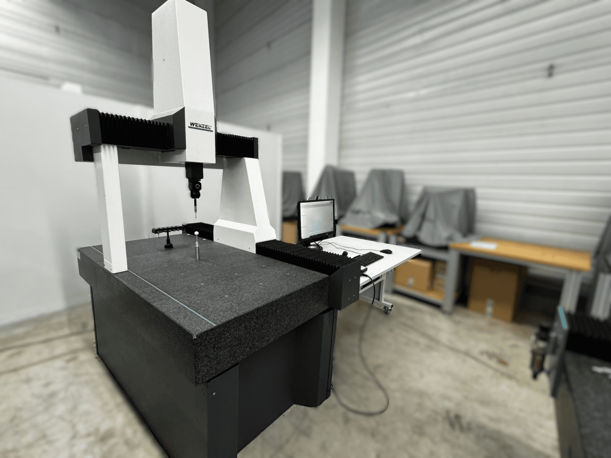 Macchina di misura a coordinate Wenzel LH 54 in una vista laterale, con una sonda e un'interfaccia per computer su una base grigia.