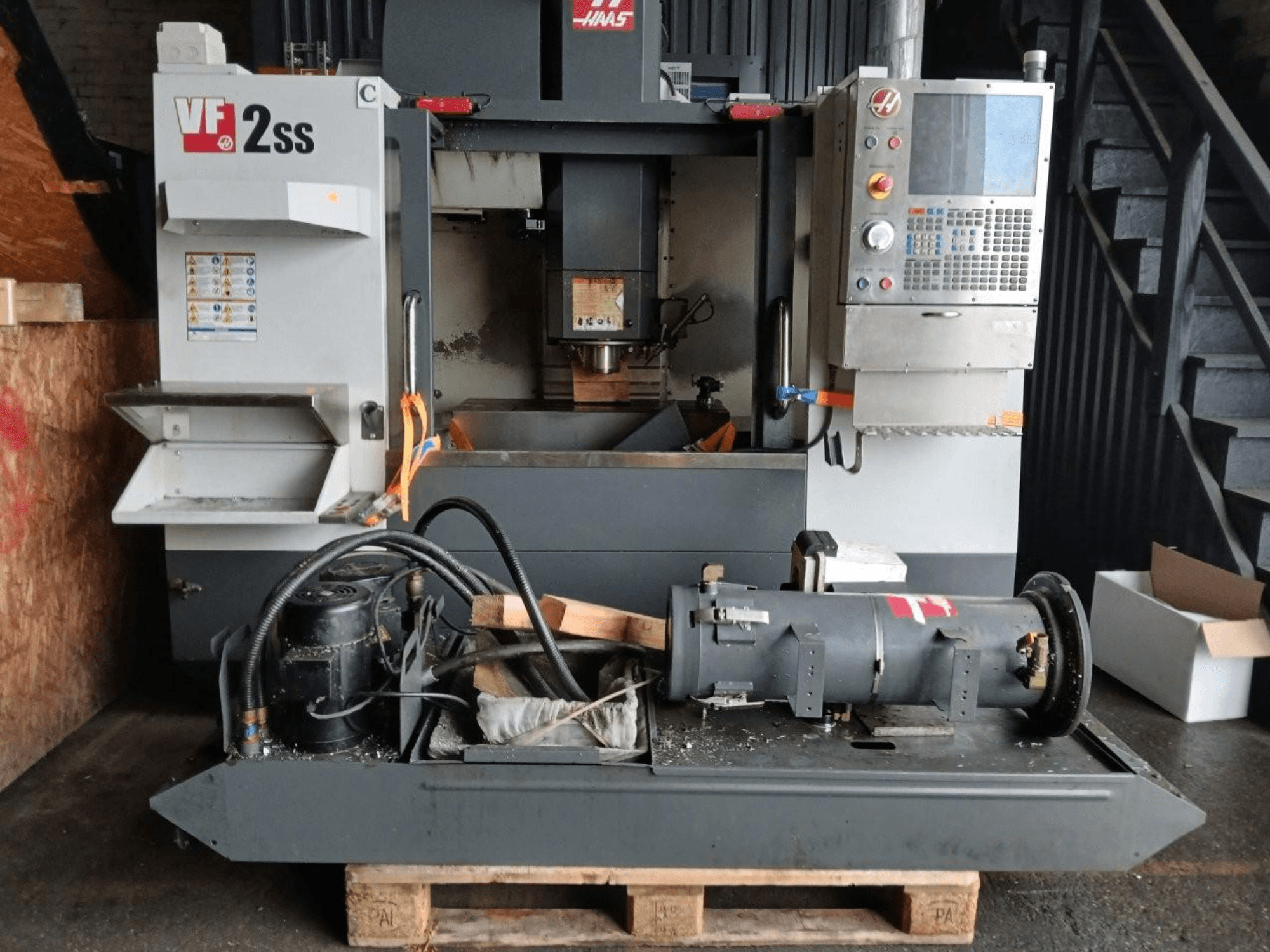 Centro di lavoro verticale HAAS VF-2SS in vista frontale, con pannello di controllo, area del mandrino e componenti del motore collegati.