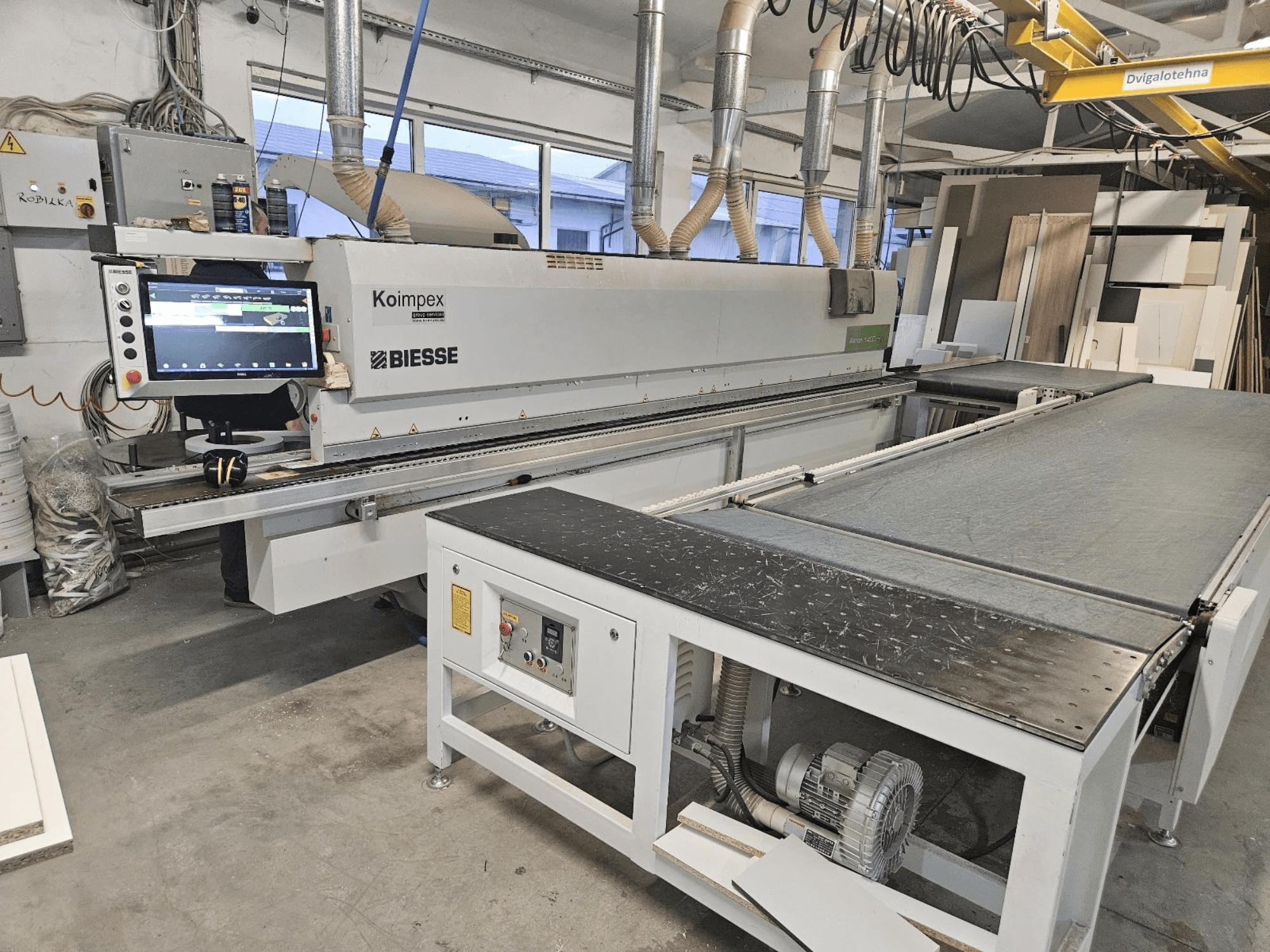 BIESSE Akron 1440 Una bordatrice in officina, vista laterale che mostra il pannello di controllo e il nastro trasportatore.