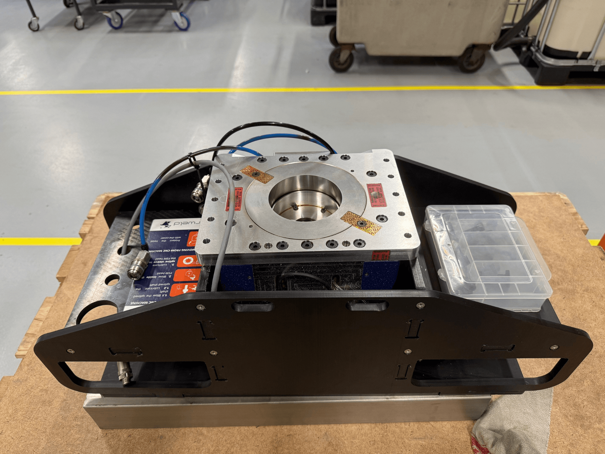 Componente in metallo lavorato con cavi blu, custodia per accessori e base piatta, vista dall'alto, ideale per applicazioni meccaniche.