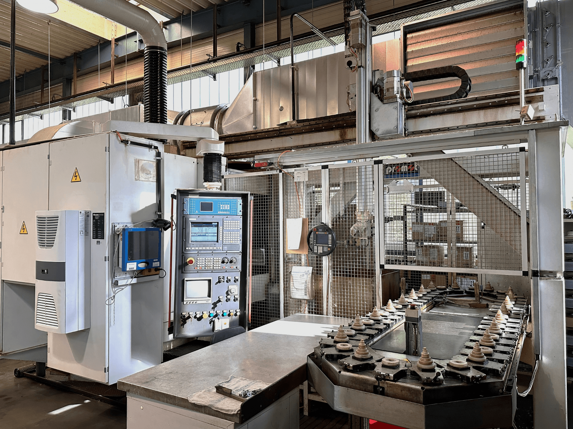 Macchinario industriale con pannello di controllo, unità di raffreddamento e trasportatore. Vista frontale, con luci luminose e segnaletica di sicurezza.