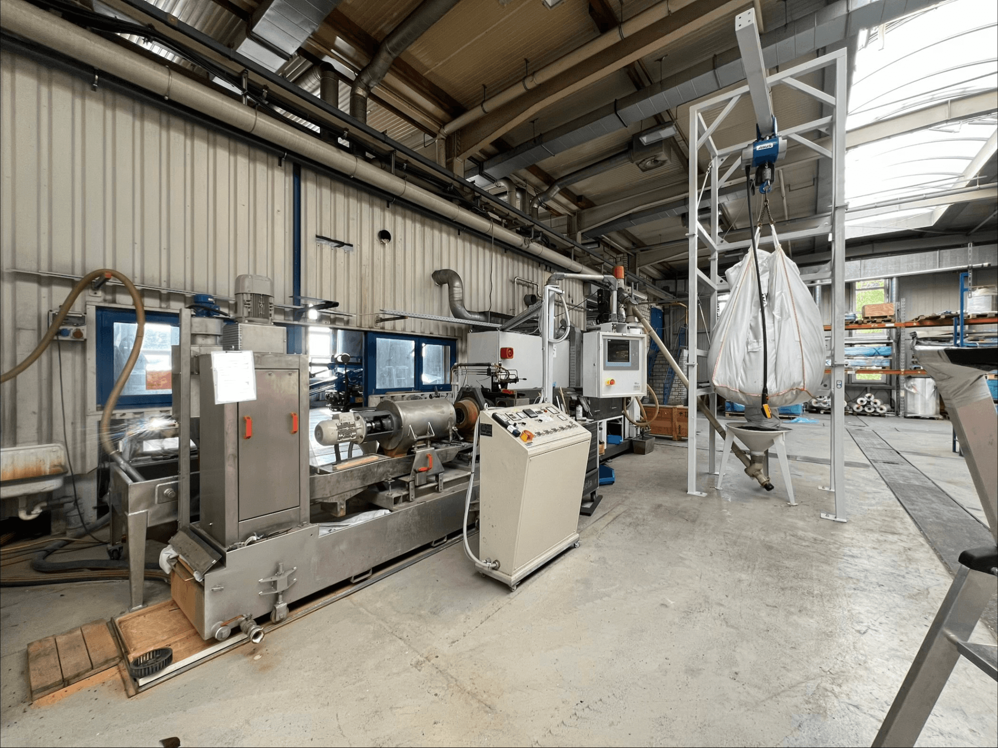 Vista frontale della macchina per la lavorazione della plastica FILTEC GRP 350 in un ambiente industriale, con i comandi e il sistema di alimentazione.