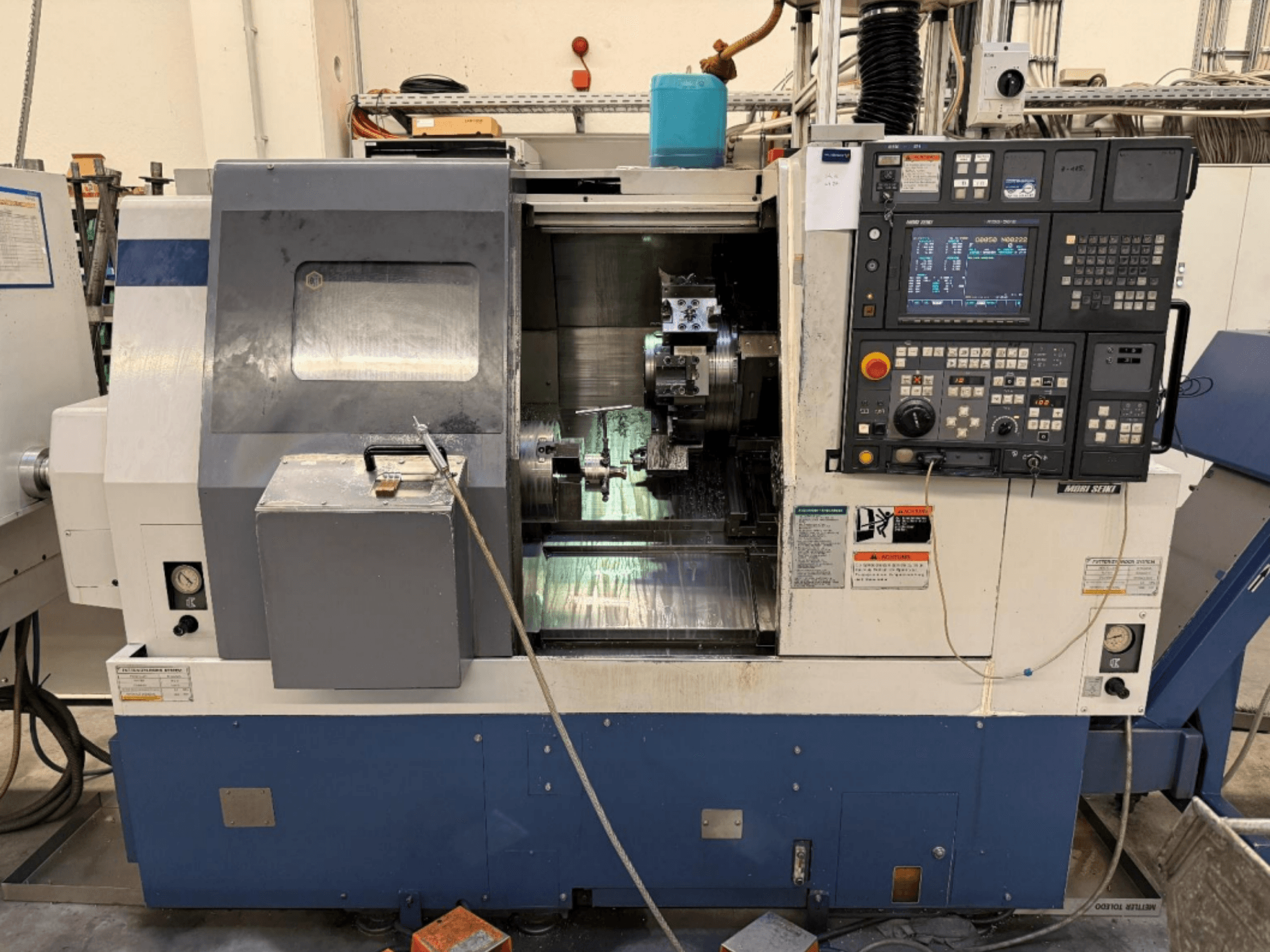 Centro di tornitura e fresatura MORI SEIKI SL-250ASMC, vista frontale che mostra il pannello di controllo e il mandrino portapezzo in funzione.