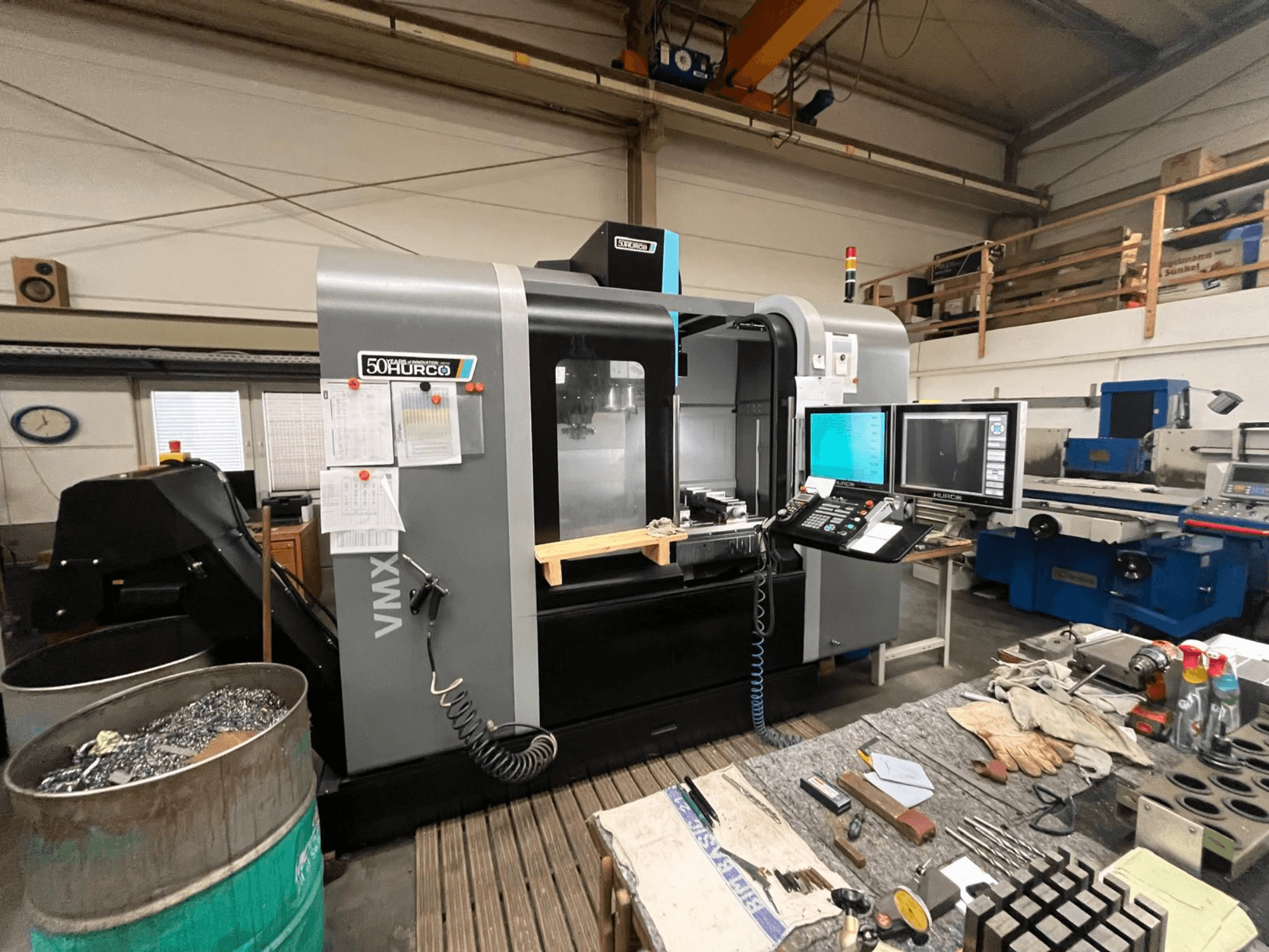 Fresatrice CNC Hurco VMX 50 in un'officina, vista frontale con pannello di controllo e banco di lavoro ingombro.