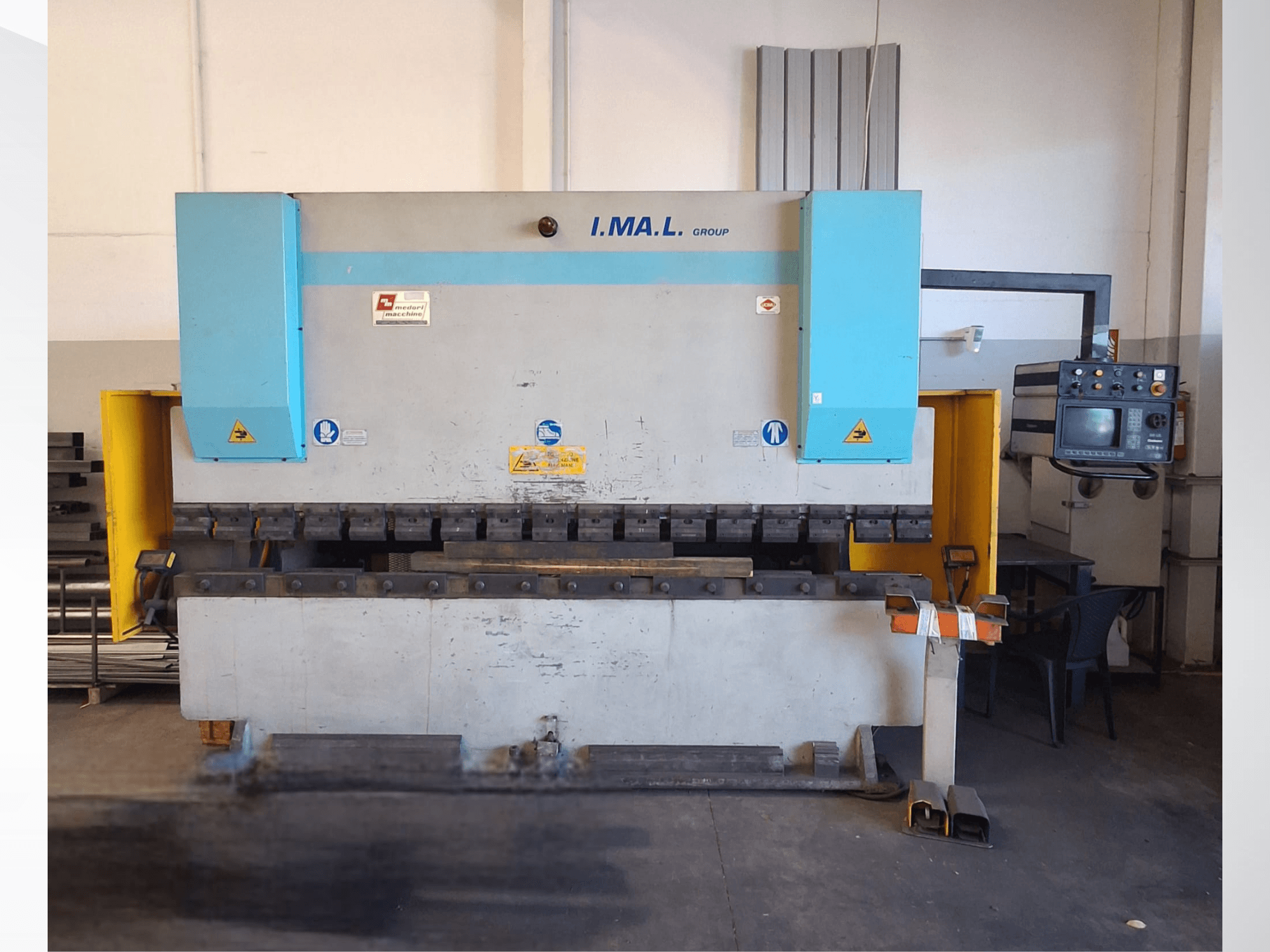 Vista frontale di una pressa piegatrice IMAL E3A 100/33, con pannello di controllo, utensili di piegatura e segnaletica di sicurezza.