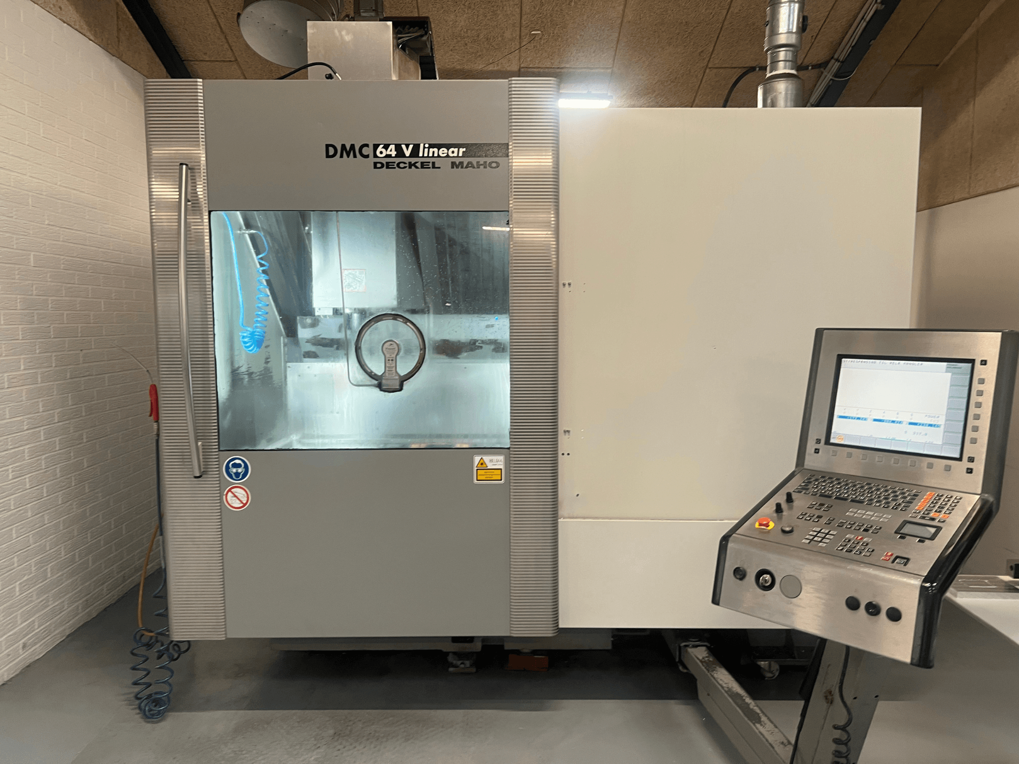 DMC 64 V Linear di Deckel Maho, vista frontale del centro di lavoro CNC con pannello di controllo e ugello del refrigerante visibili.
