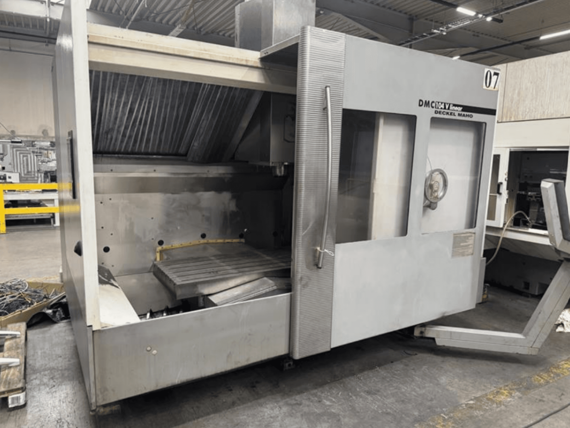 Macchina lineare DMC 104 V di Deckel Maho, vista frontale, caratterizzata da un'area di lavorazione vuota con un grande tavolo di lavoro.