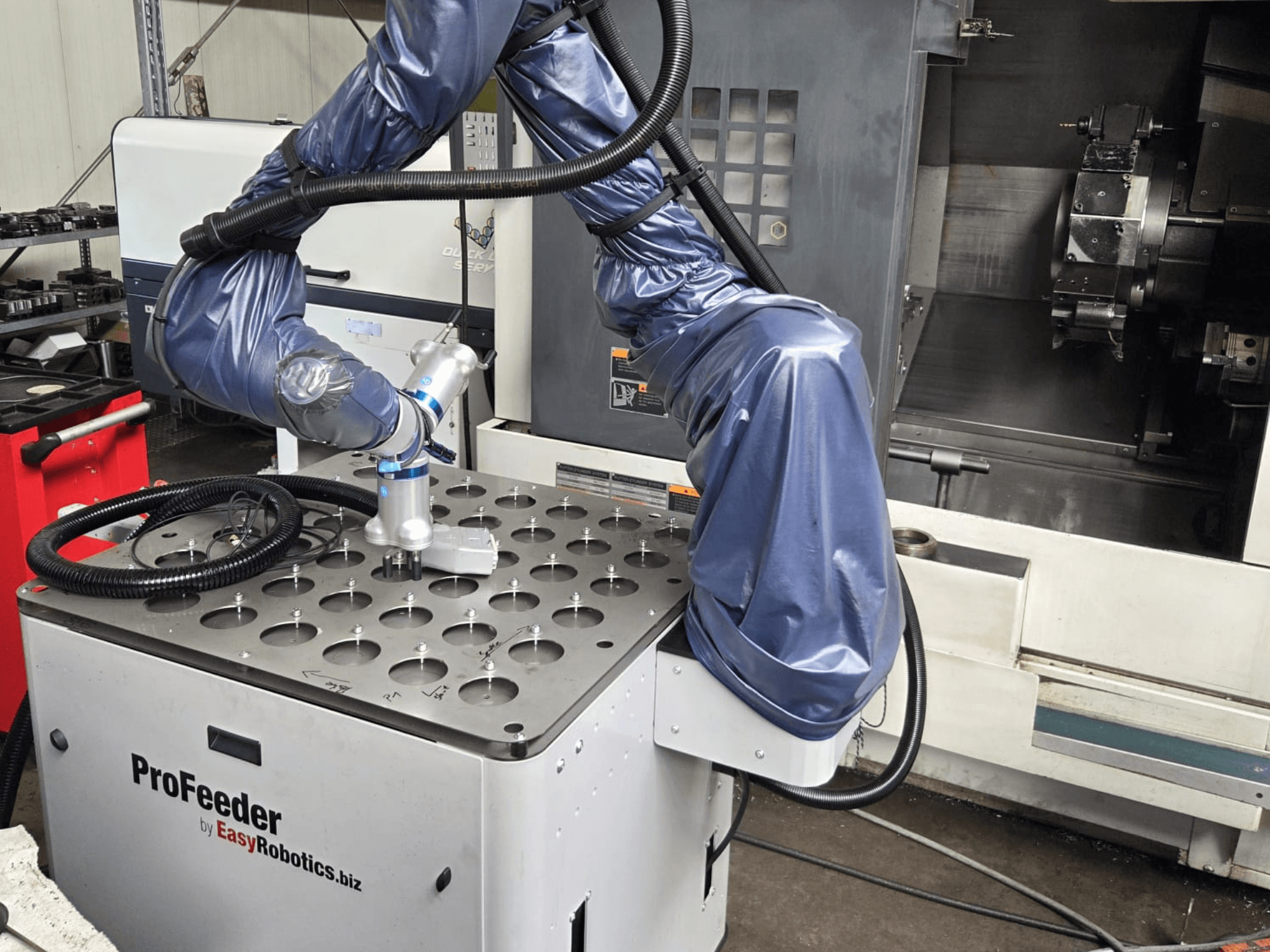 Robot collaborativo EASYROBOTICS ProFeeder da una vista frontale, con un braccio robotico posizionato su un tavolo di metallo perforato.