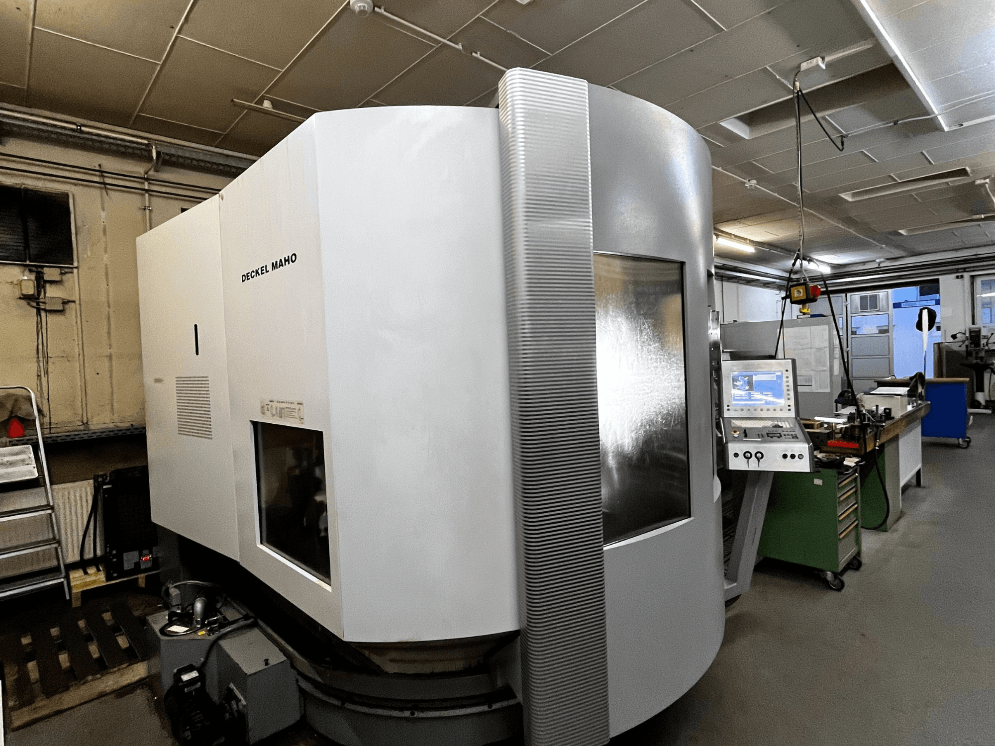 Macchina CNC Deckel Maho, vista frontale, esterno bianco, pannello di controllo visibile, ambientazione in officina.