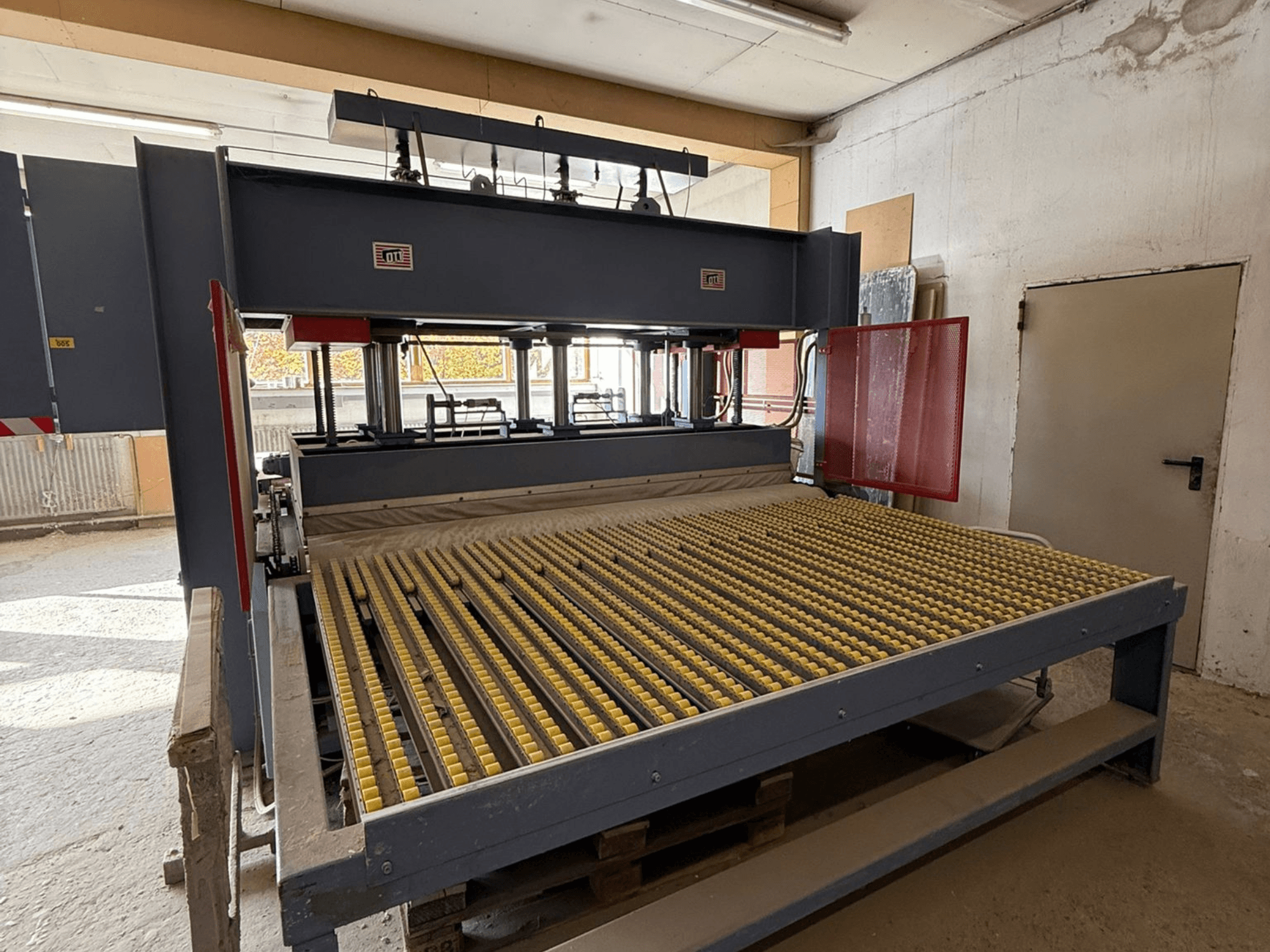 Macchina industriale con rulli gialli, vista frontale, logo del marchio visibile, utilizzata per la lavorazione di materiali in un'officina.