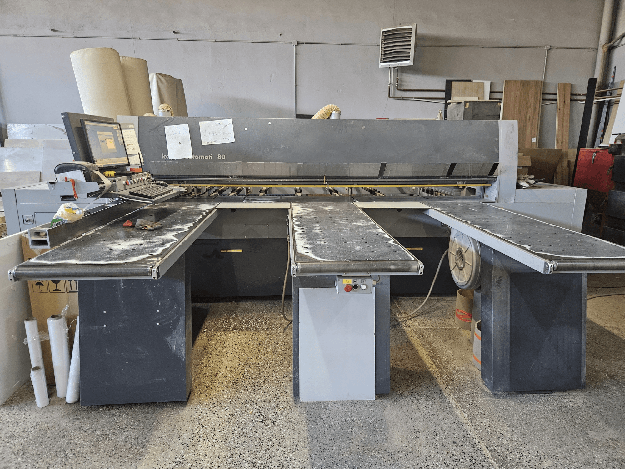Macchina KAPPA Automati 80, vista frontale, con tre tavoli piani, pannello di controllo e segatura sparsa sulle superfici.