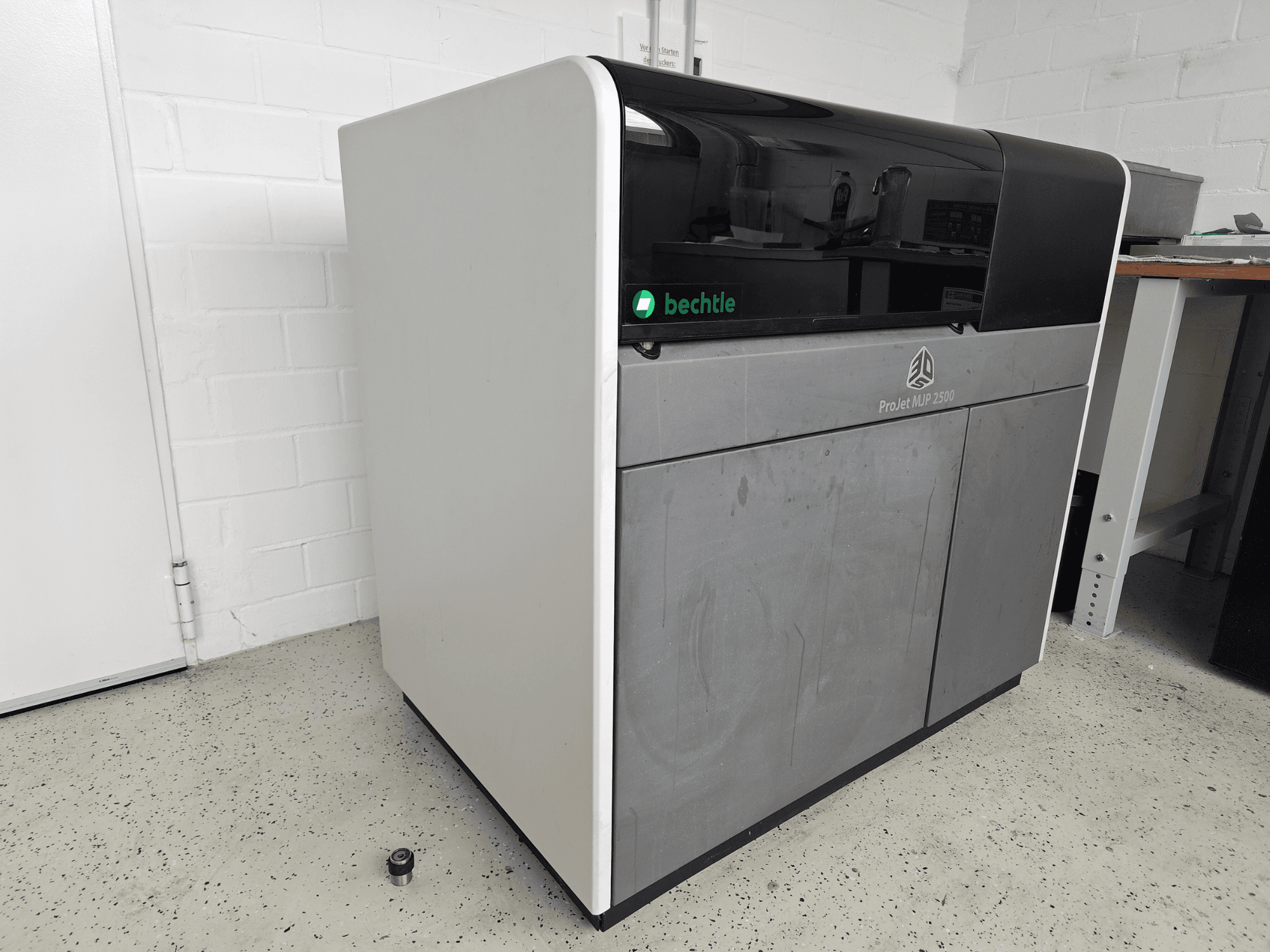 Stampante 3D per plastica 3D Systems ProJet MJP 2500 Plus vista frontale; presenta un design elegante con la parte superiore scura e il corpo chiaro.