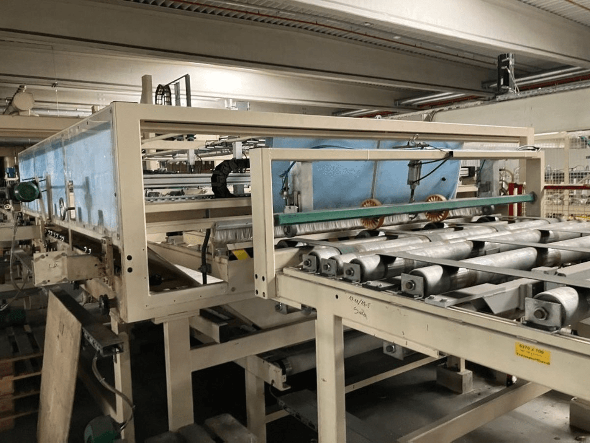 Pressa di laminazione WEMHÖNER KT-F-1E, vista laterale, con rulli e comandi per la lavorazione del materiale in fabbrica.