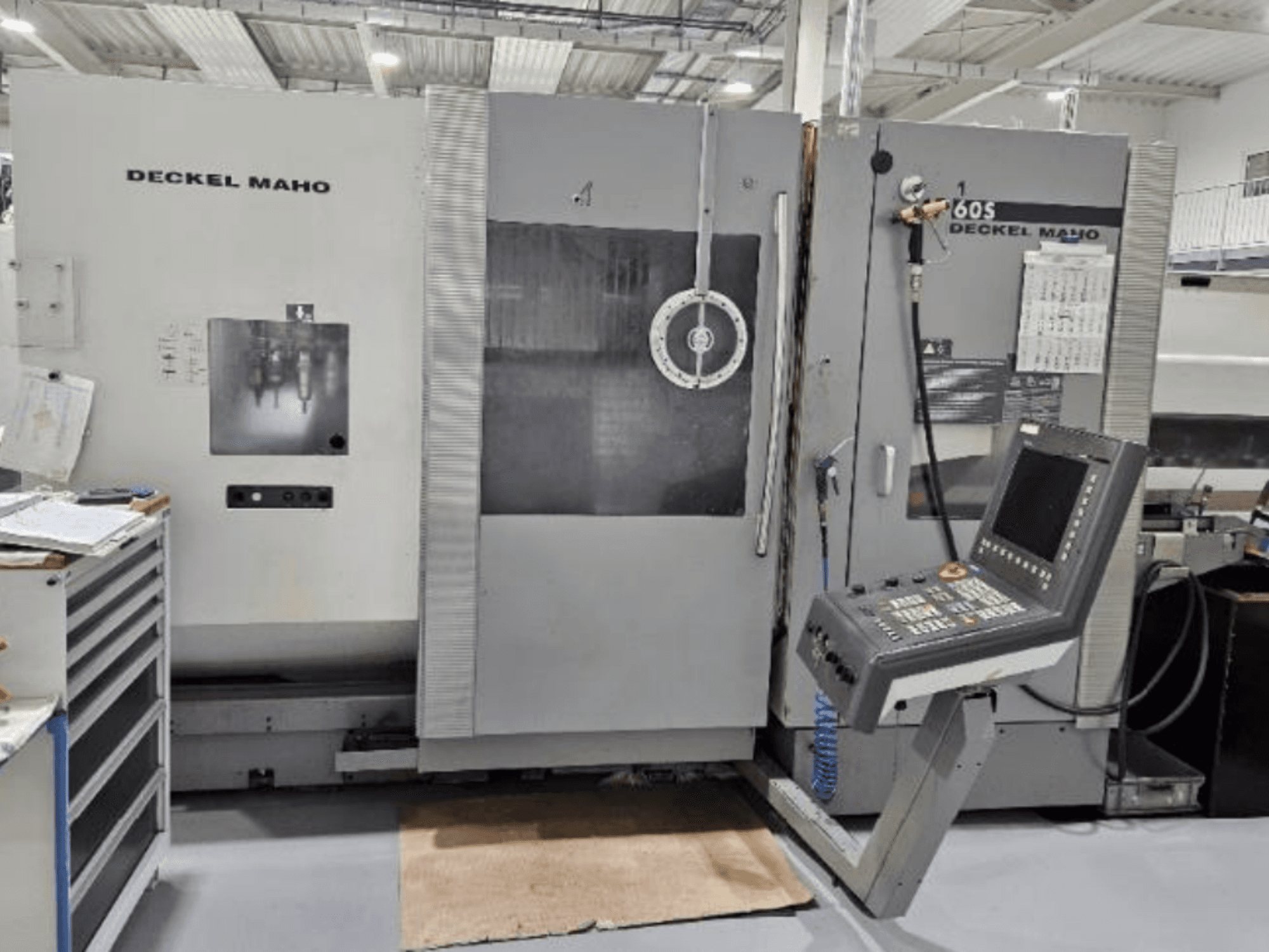 Vista frontale di una macchina CNC DECKEL MAHO 60S con pannello di controllo, utensili visibili, in un'officina.