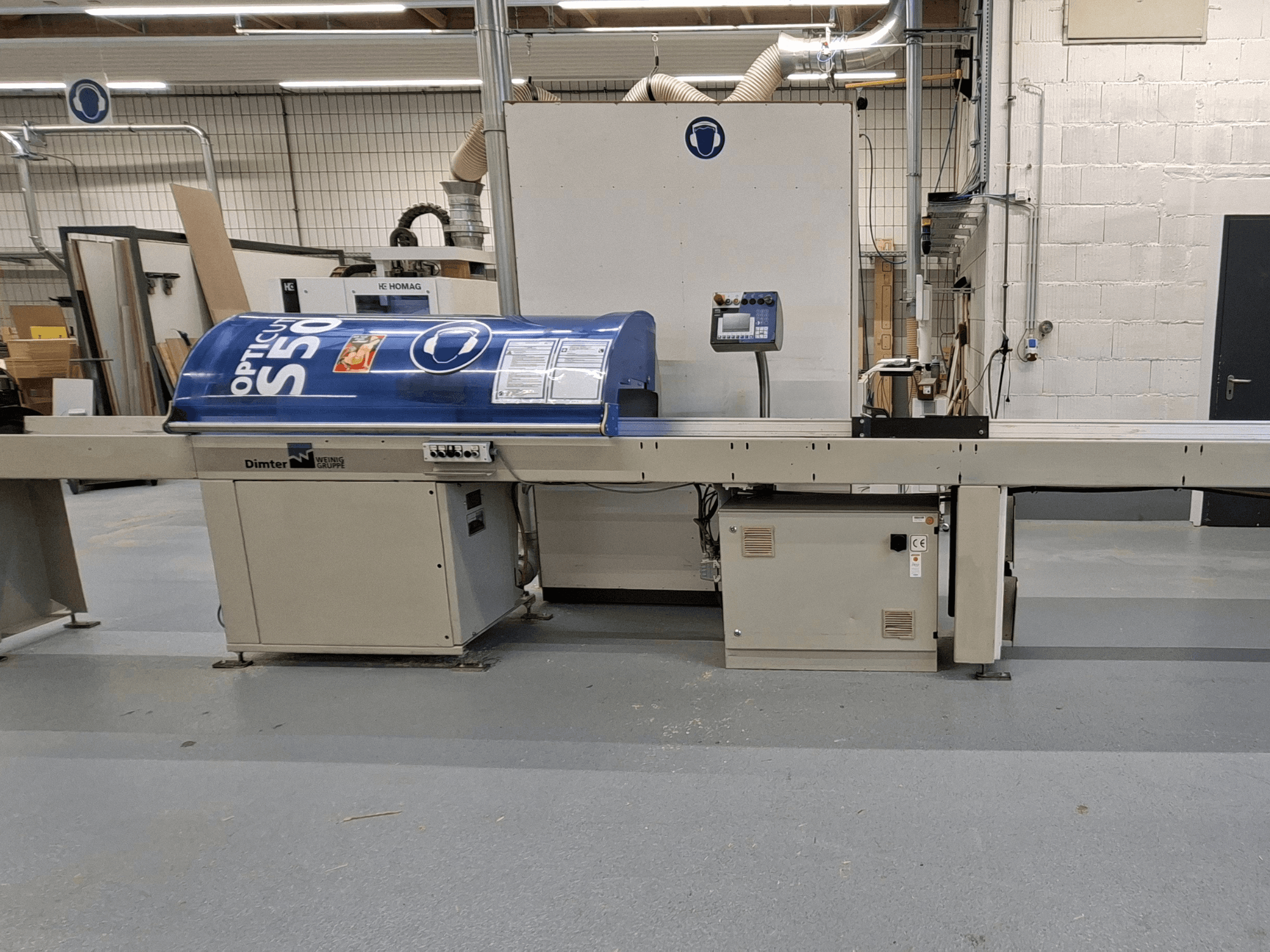 Macchina per il taglio del legno Dimter OptiCut S50 in vista laterale, con alloggiamento blu, pannello di controllo e nastro trasportatore.