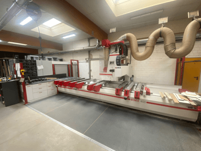 Macchina CNC BIMA 400 vista frontalmente, caratterizzata da un design rosso e bianco e da un sistema di aspirazione delle polveri.