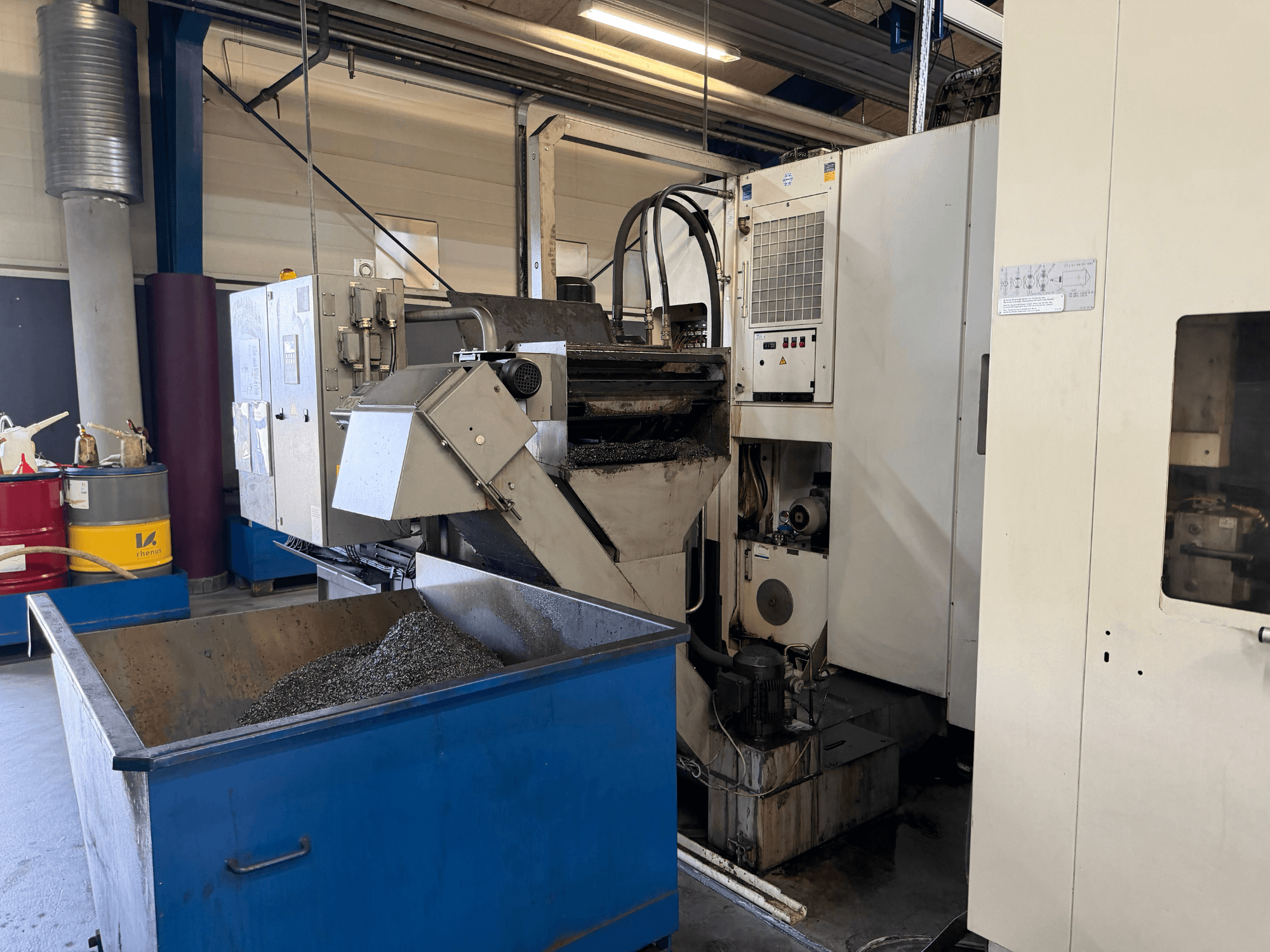 Vista frontale del centro di lavoro orizzontale HELLER MCH 250 con il contenitore di riciclaggio del refrigerante metallico e il pannello di controllo visibili.