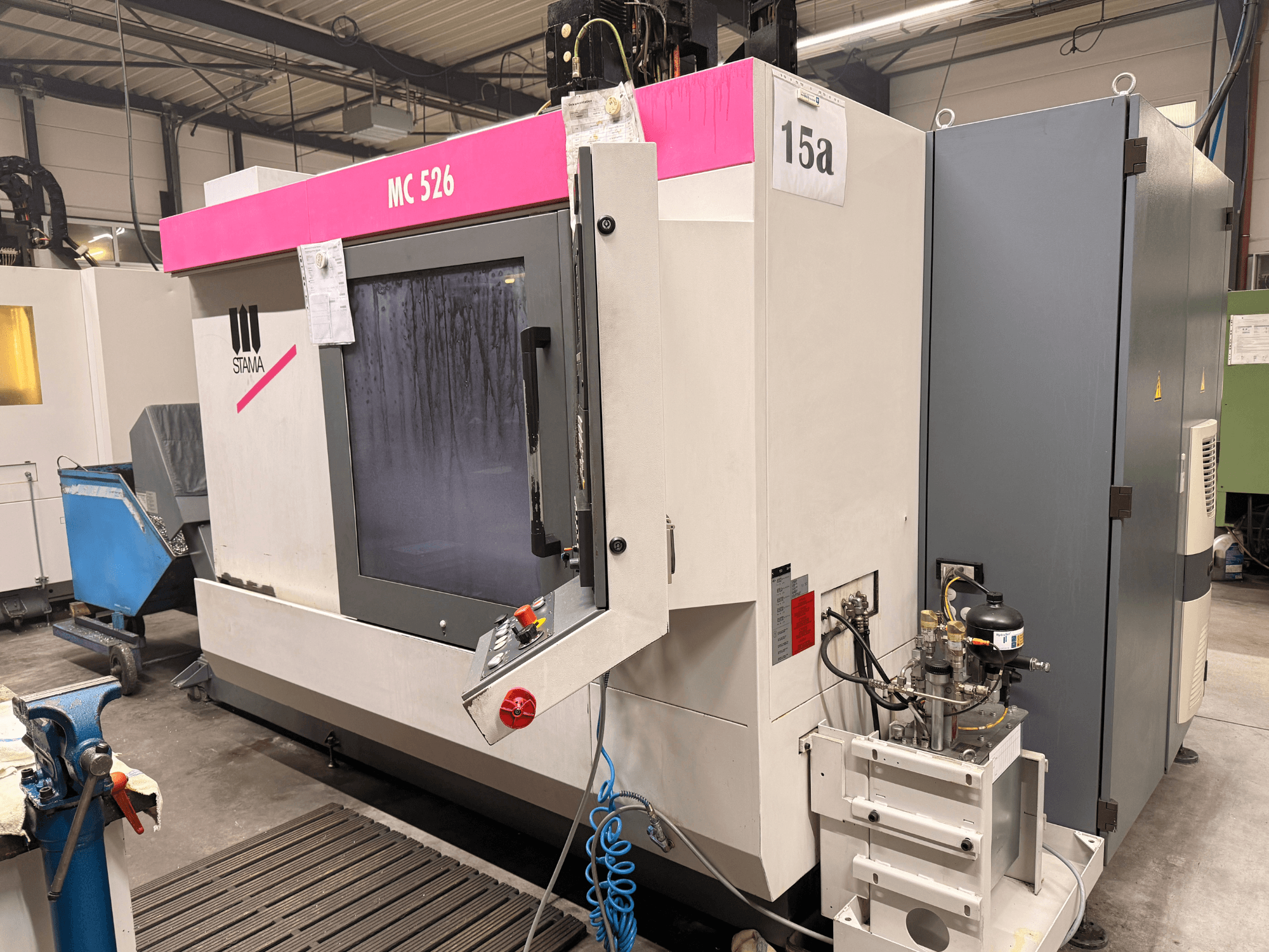 Centro di lavoro Stama MC 526 in un'officina, vista frontale, con pannello di controllo e quadro elettrico grigio adiacente.