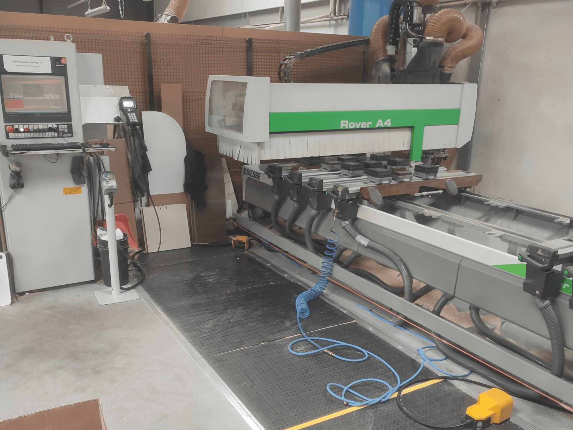 Centro di lavorazione del legno CNC BIESSE Rover A4 visto di profilo, con pannello di controllo, dispositivi di fissaggio a vuoto e sistema di aspirazione delle polveri.
