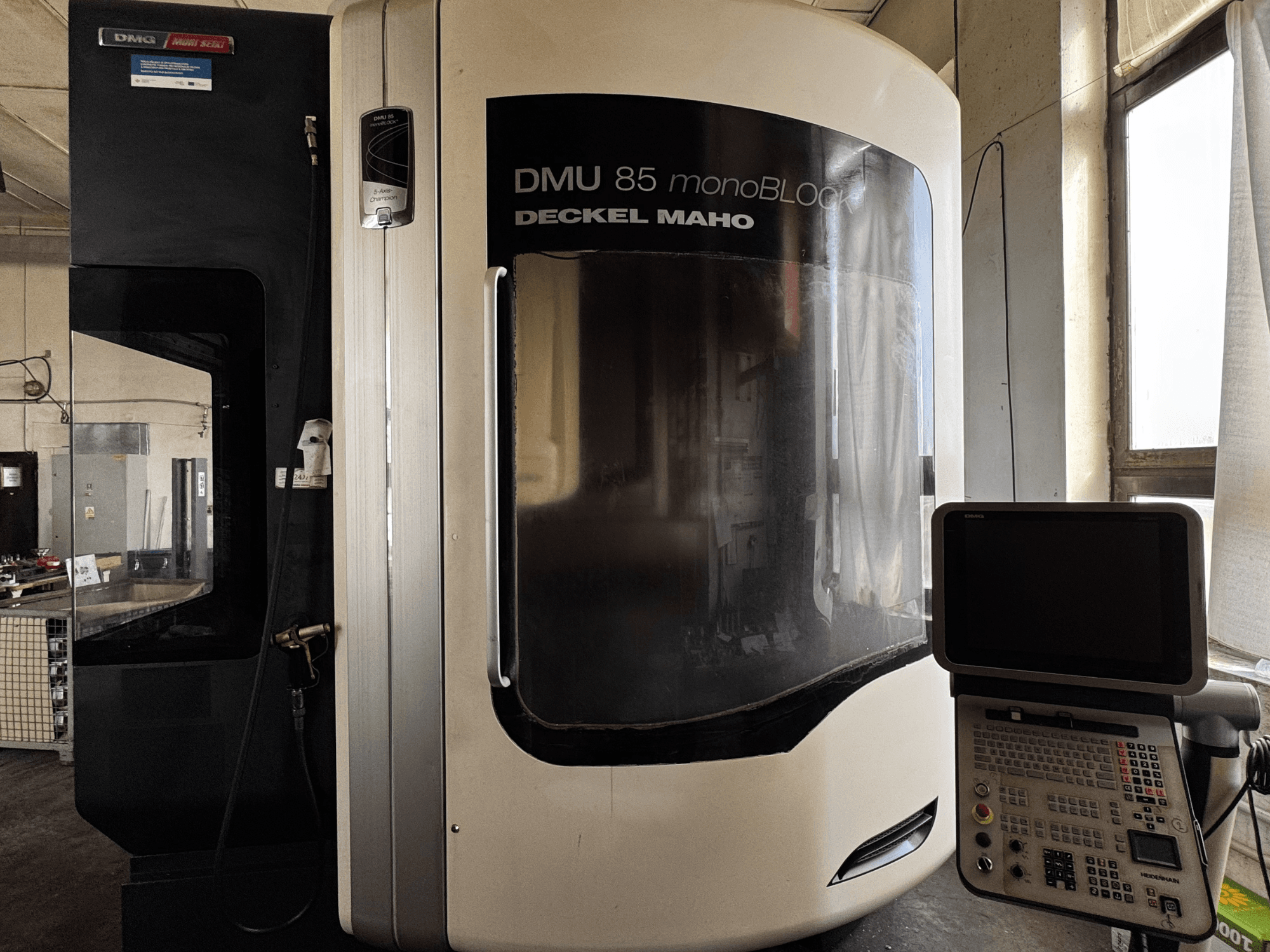 Centro di lavoro verticale DMG MORI DMU 85 monoBLOCK, vista frontale con pannello di controllo e ampia finestra di visualizzazione.
